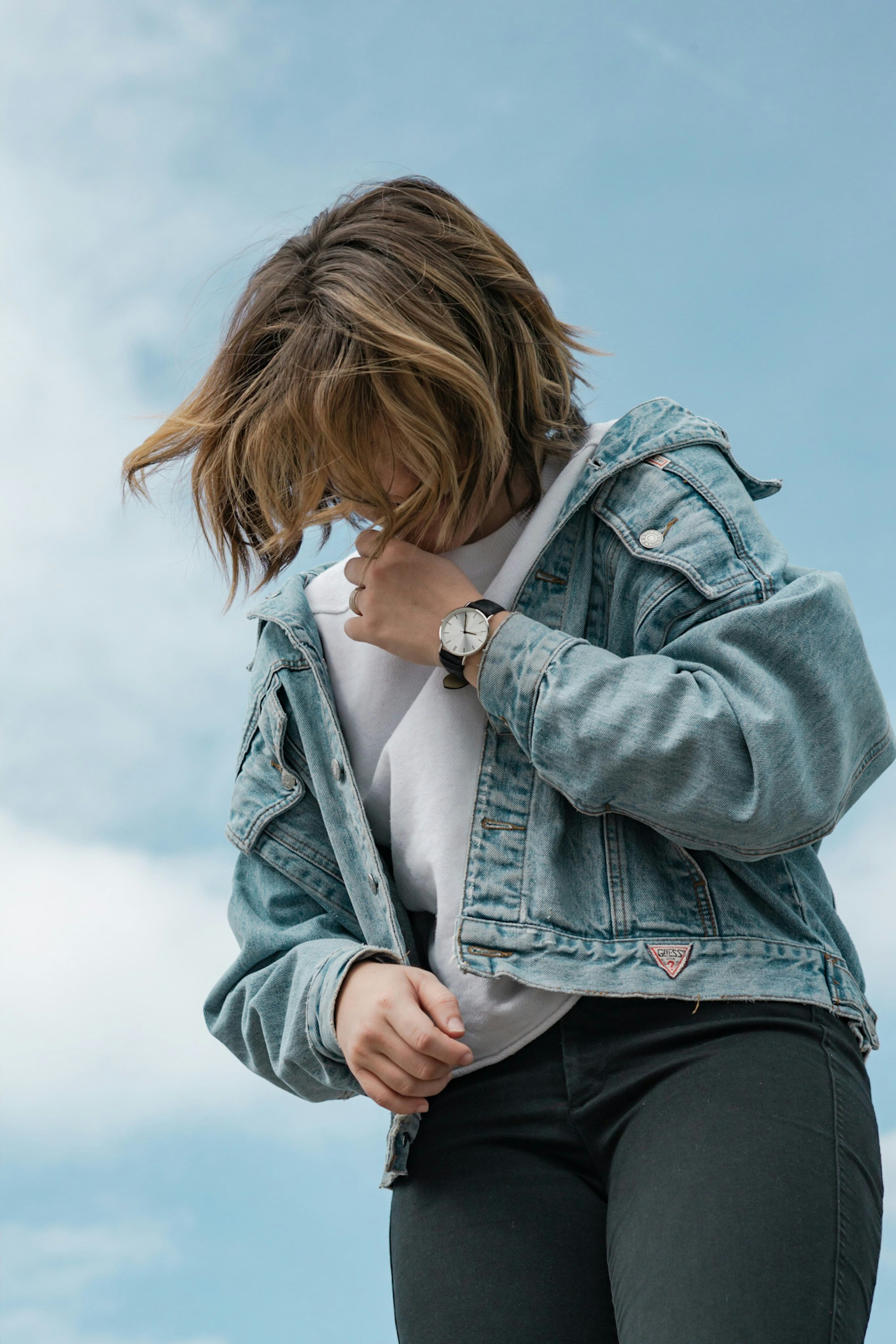 Model in a white T-shirt and denim jacket looking down