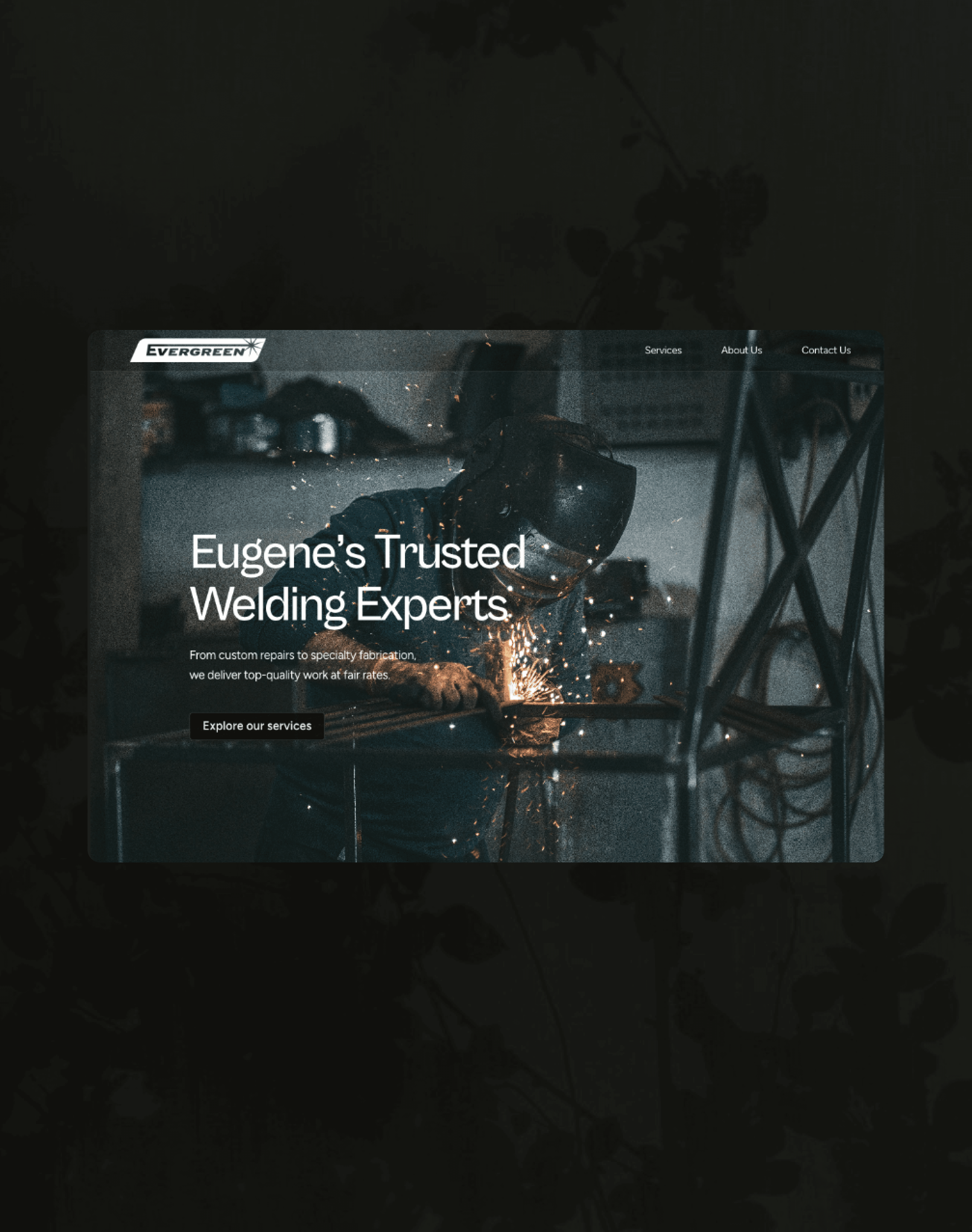 A young person with curly hair smiles at the camera while sitting in front of a laptop against a dark background.