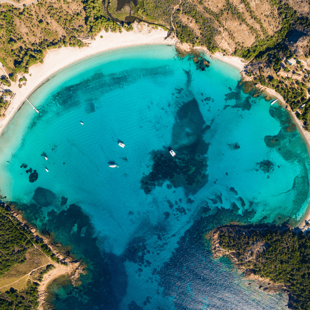 Vue aérienne d’une anse turquoise entourée de végétation en Méditerranée, lieu préservé propice au reset mental