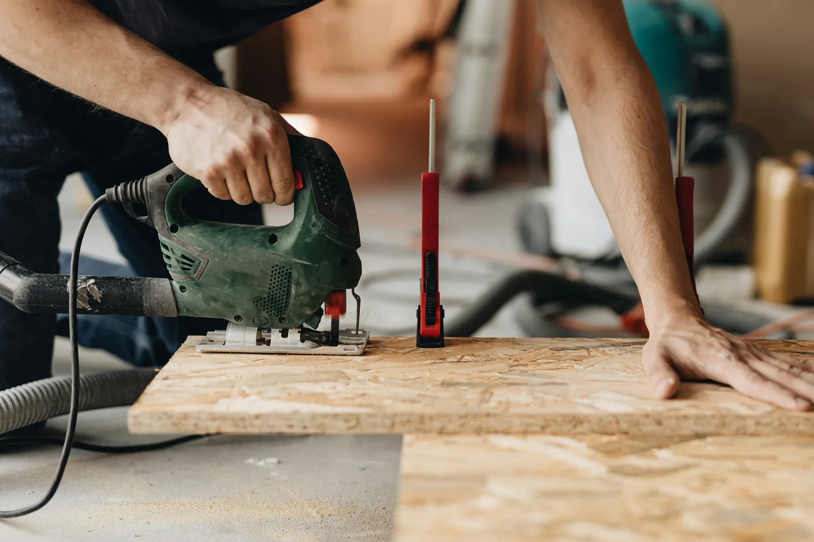 Worker cutting OSB board with jigsaw on renovation site