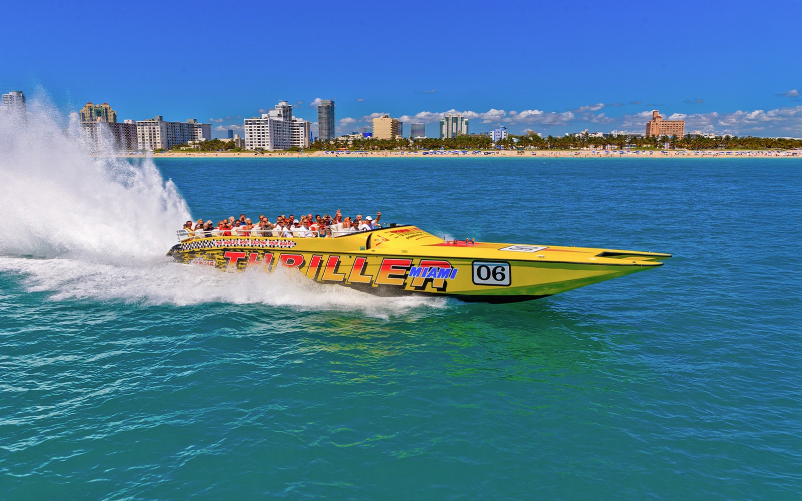 Speedboat with tourists on Miami sightseeing tour, city skyline in background.