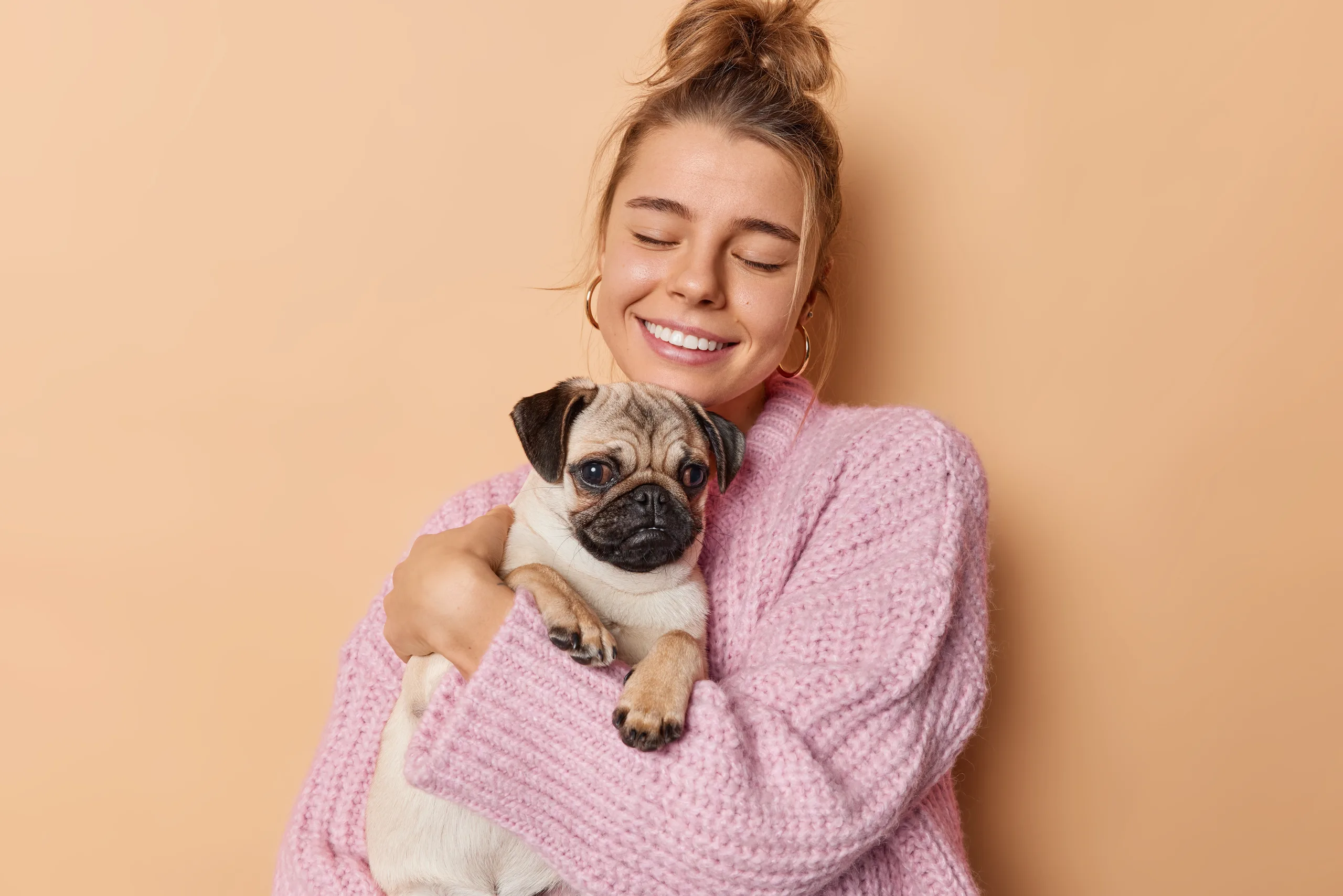 mulher sorrindo segurando cachorro pequeno
