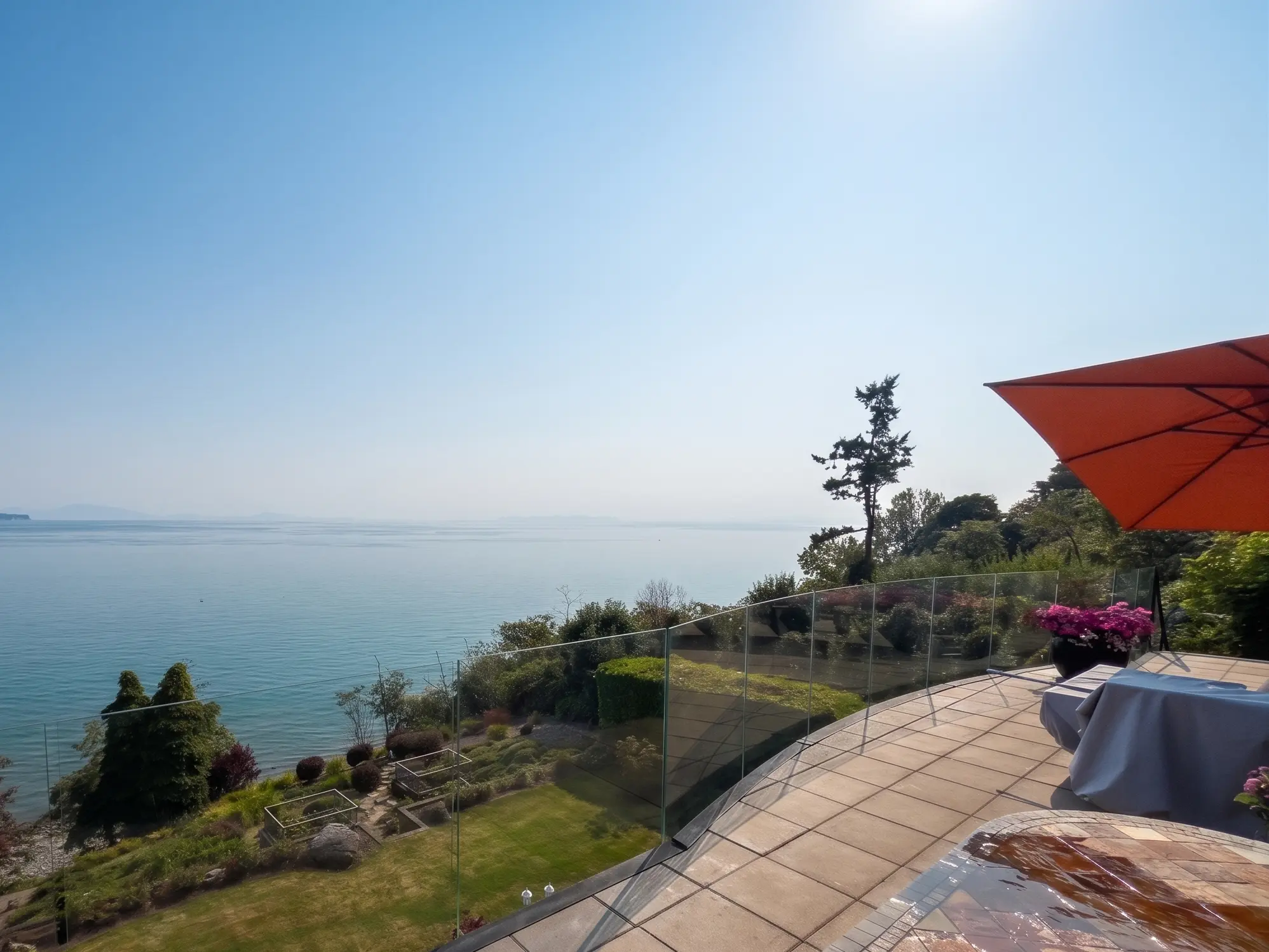 Qualicum Beach glass railings curving around a tiled oceanview patio overlooking the Strait of Georgia