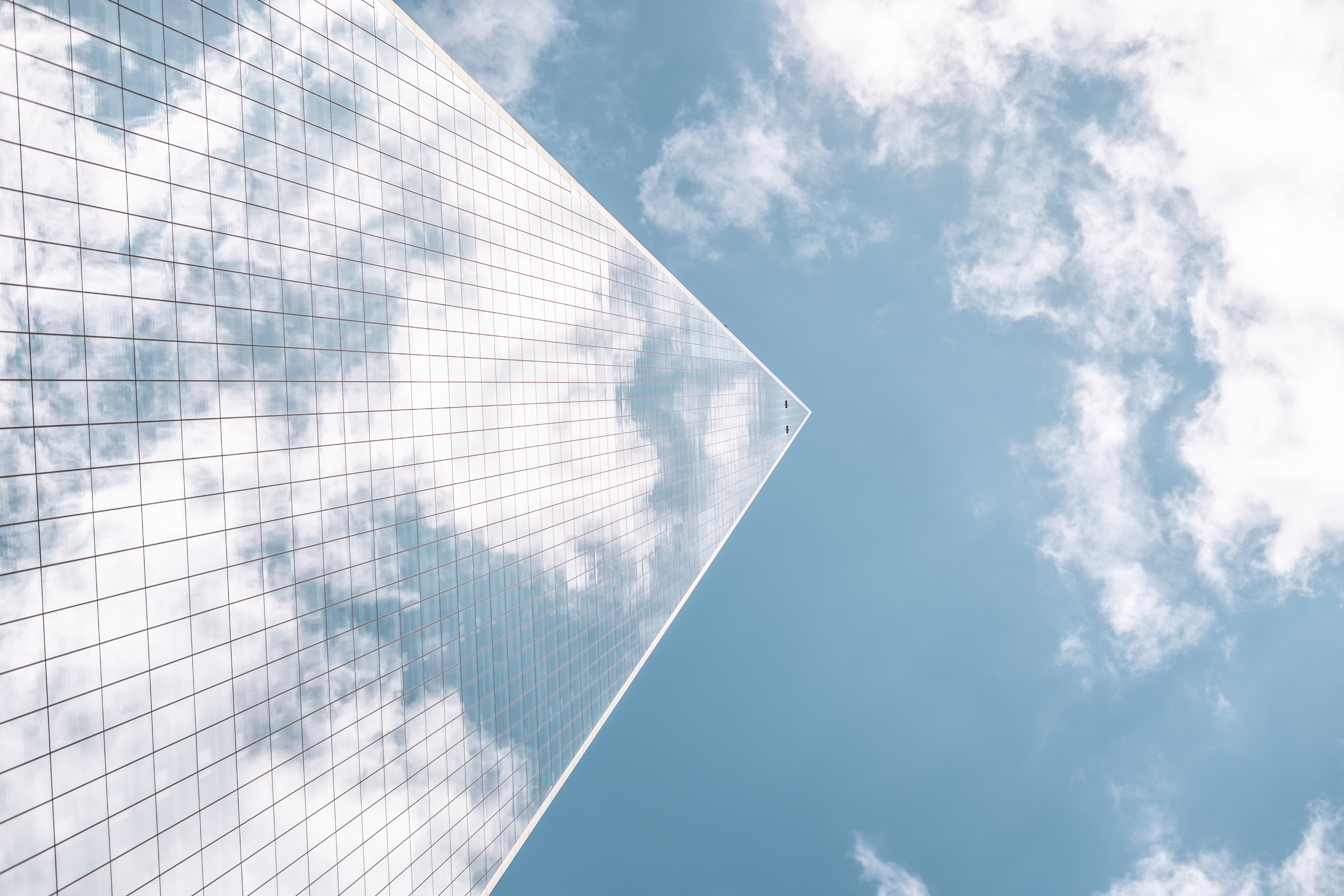 Modern glass building viewed from below against the sky, symbolising structured AI governance, oversight, and control in organisations.