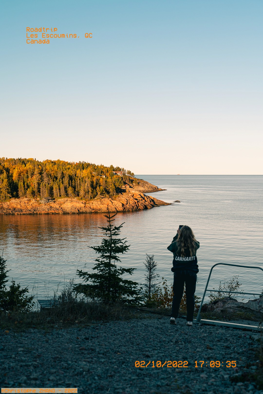 Personne photographiant la côte rocheuse des Escoumins au coucher du soleil.