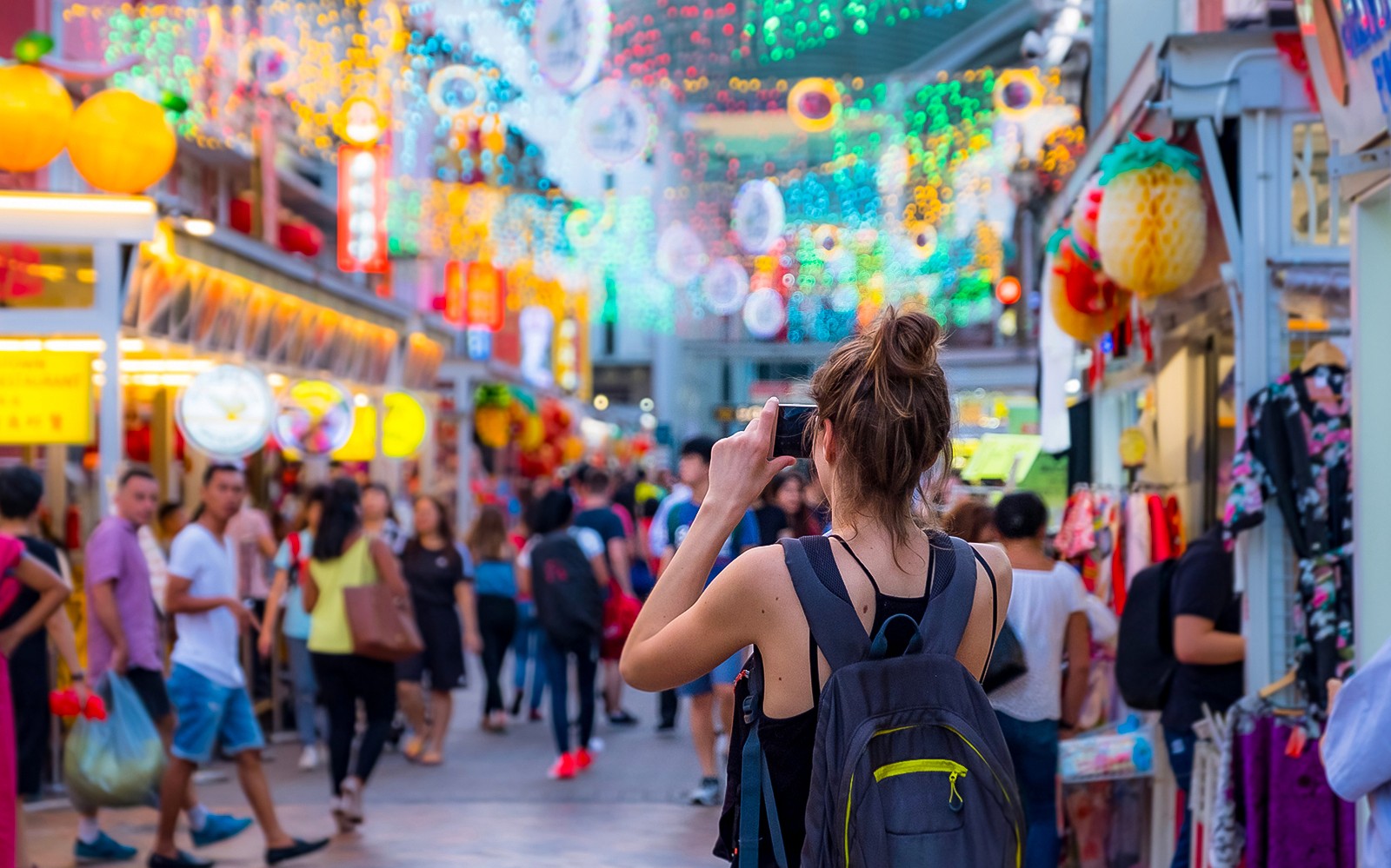 Tourist photographing vibrant street market in Singapore.