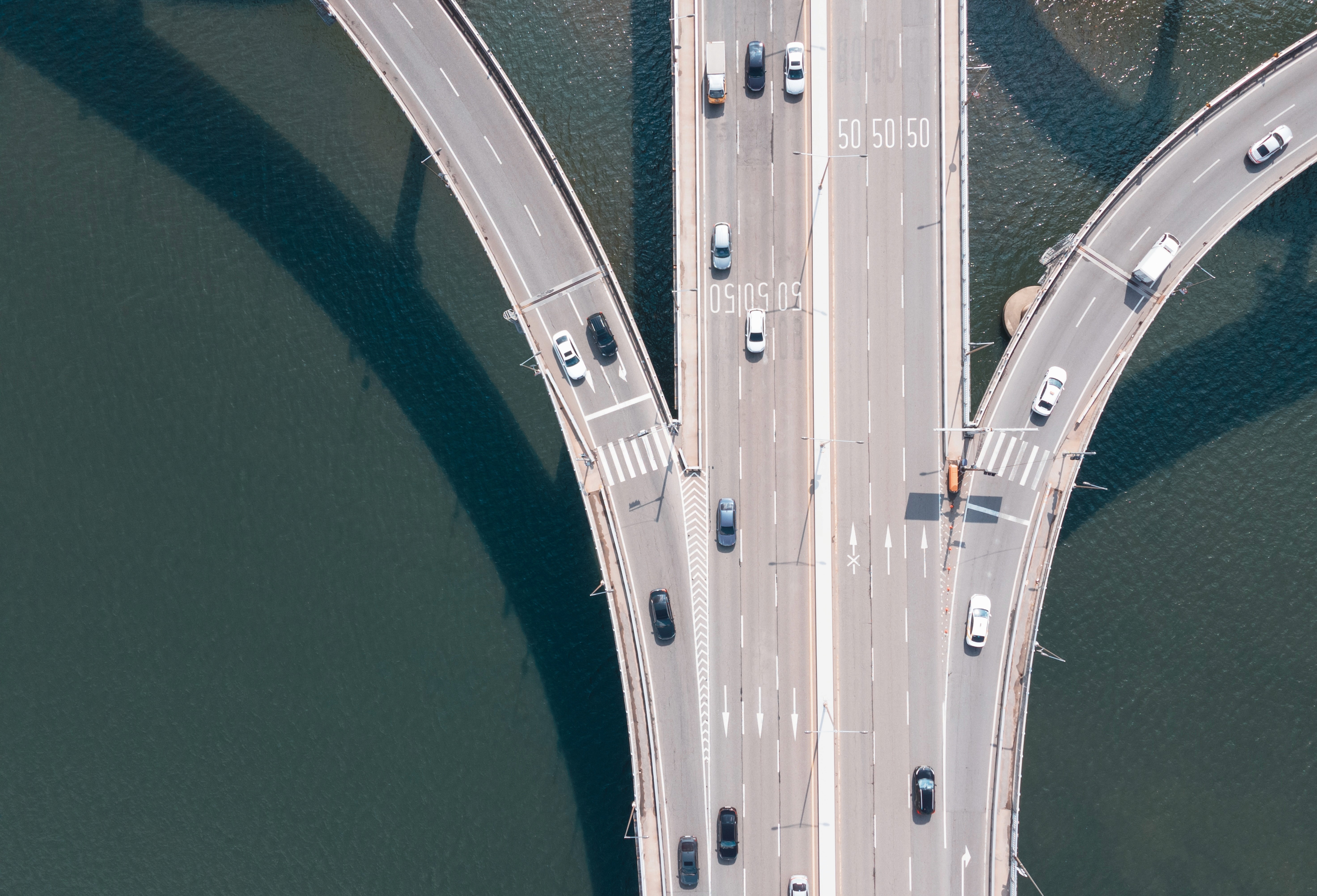 Birds eye view of a highway lanes above water splitting into three directions.