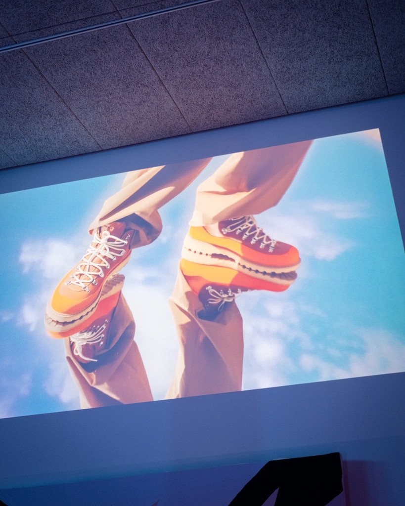 Close-up of colorful sneakers on a person standing on a surface with a blue sky background.