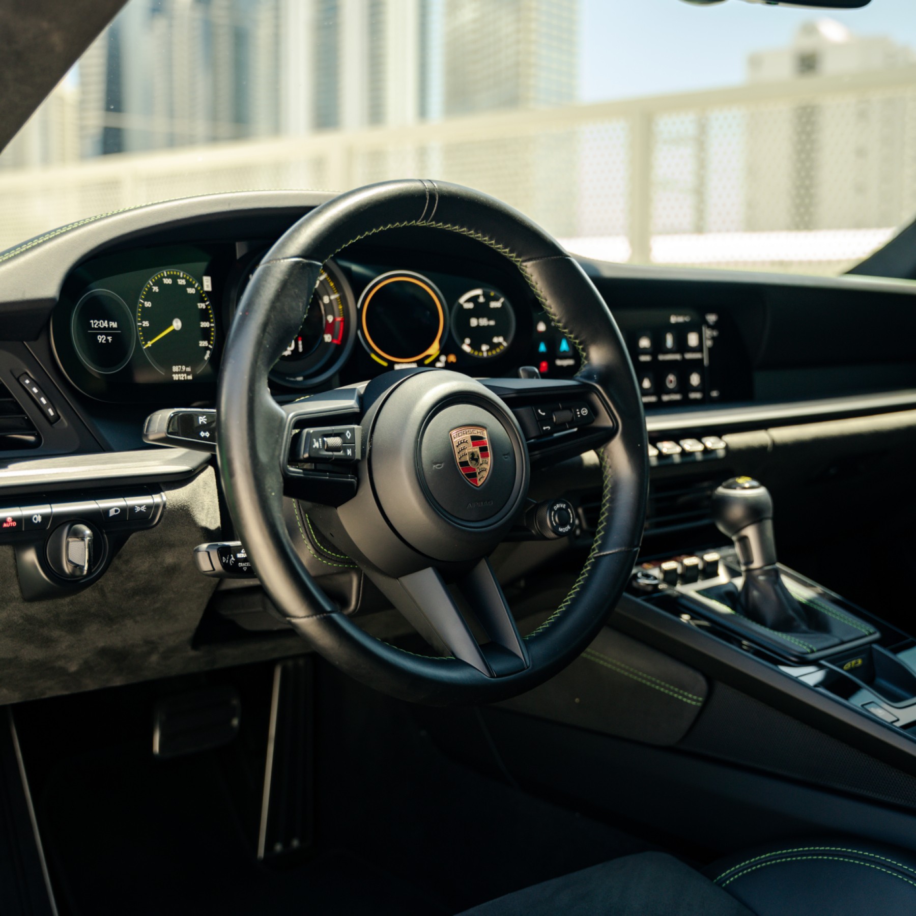 Driver-focused cockpit of the Porsche 911 GT3, black interior with green stitching, performance steering wheel.