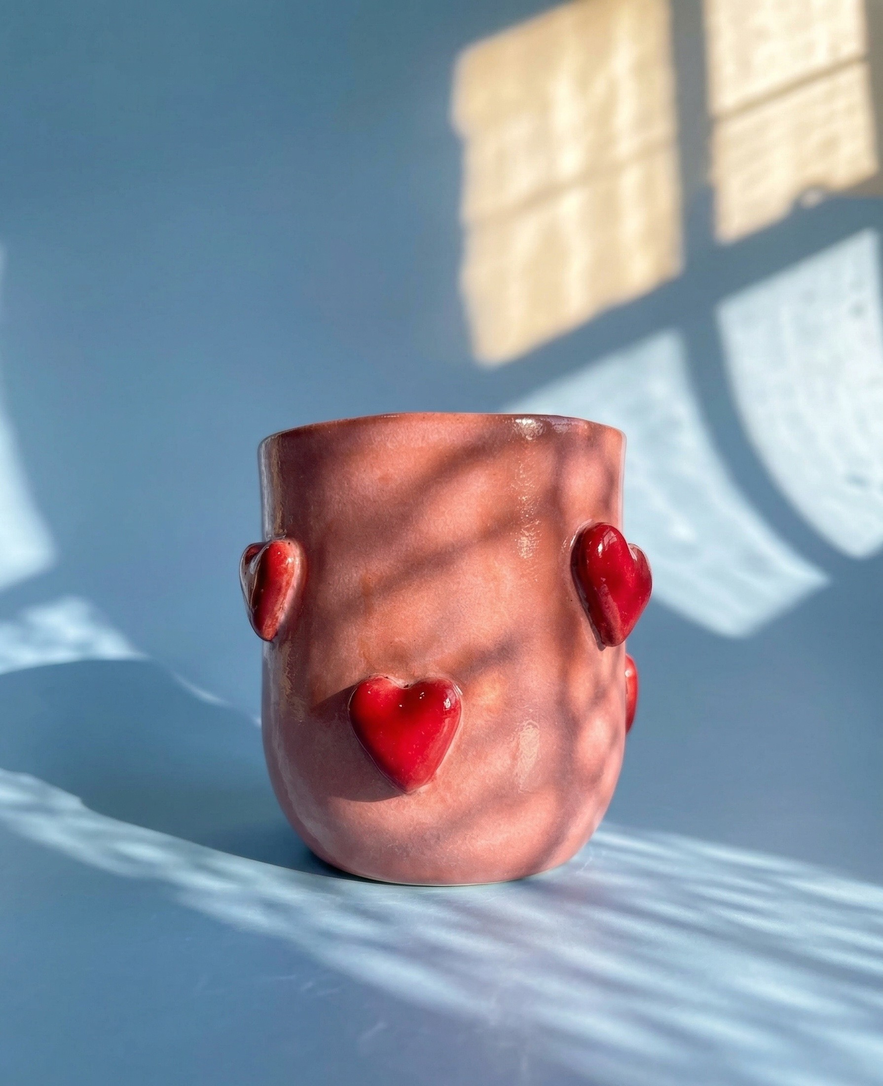 a simple ceramic cup decorated with red hearts