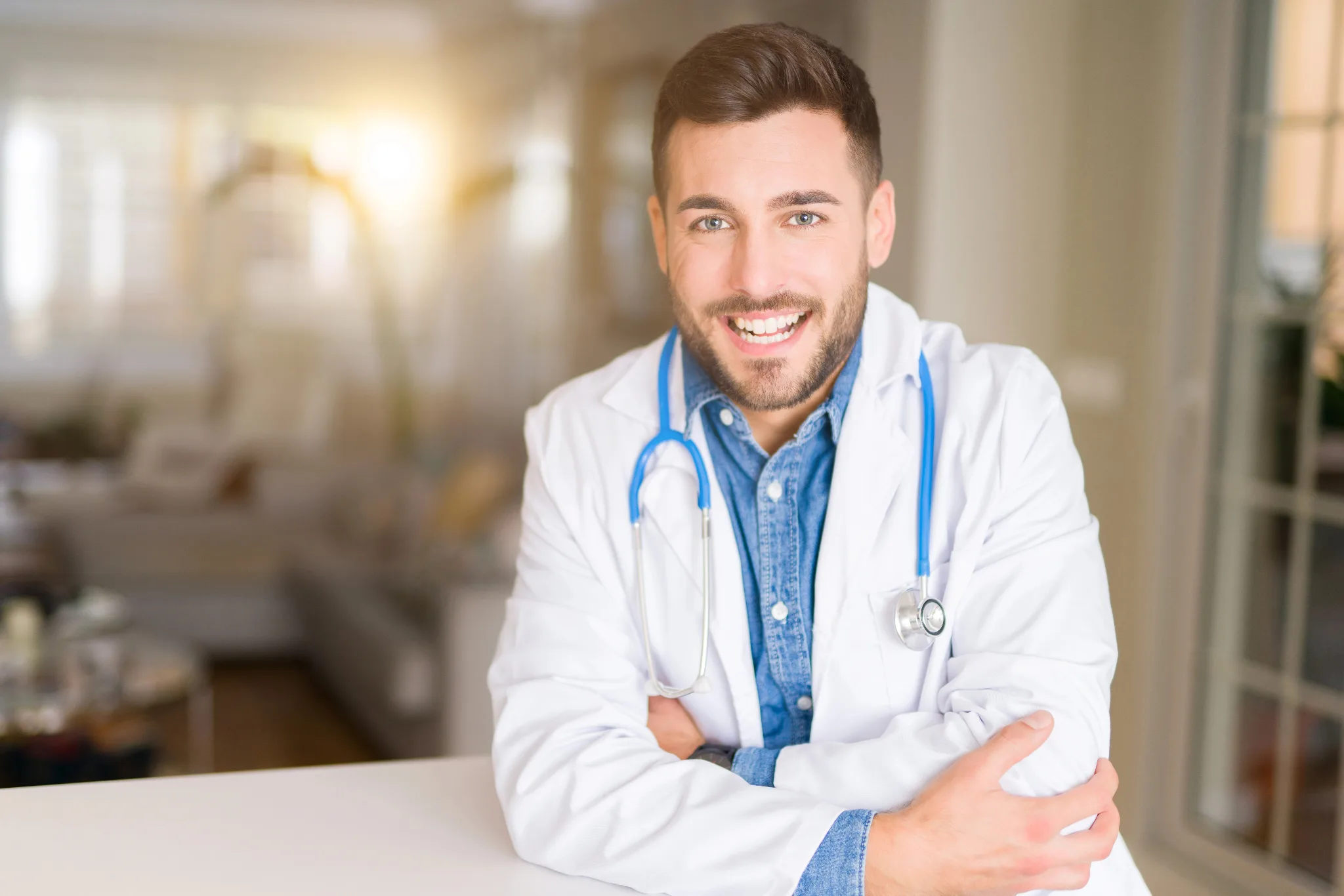 Smiling male physician in white coat with stethoscope around his neck.