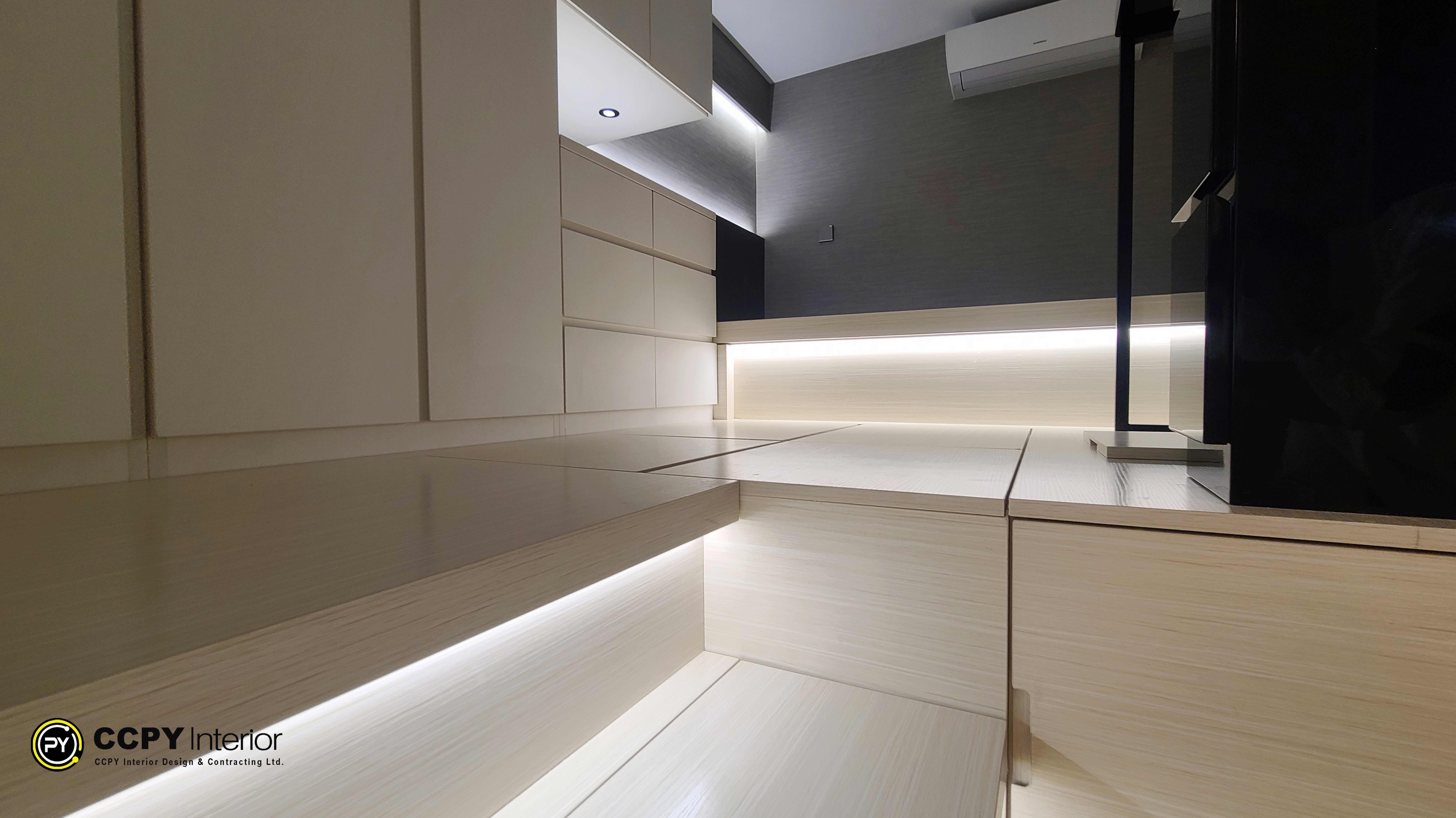 This is a custom-designed modern platform storage bed with integrated lighting by CCPY Interior Design.Platform Design: The design features a raised platform with integrated storage compartments for maximizing space efficiency.Lighting: Warm LED light strips are embedded along the edges of the platform, enhancing the atmosphere and providing subtle illumination.Color Palette: The interior uses a neutral color palette, combining wood tones and grey walls for a contemporary look