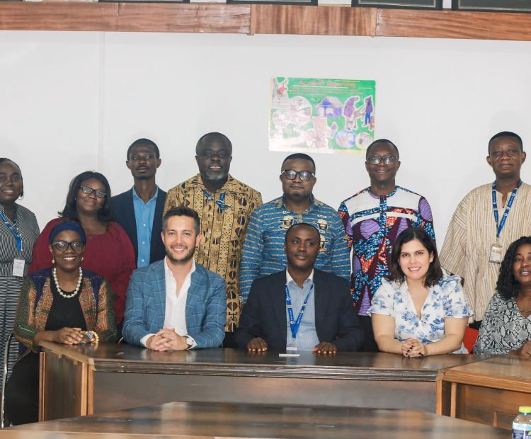 A group of diverse individuals poses together in a meeting room, smiling at the camera.