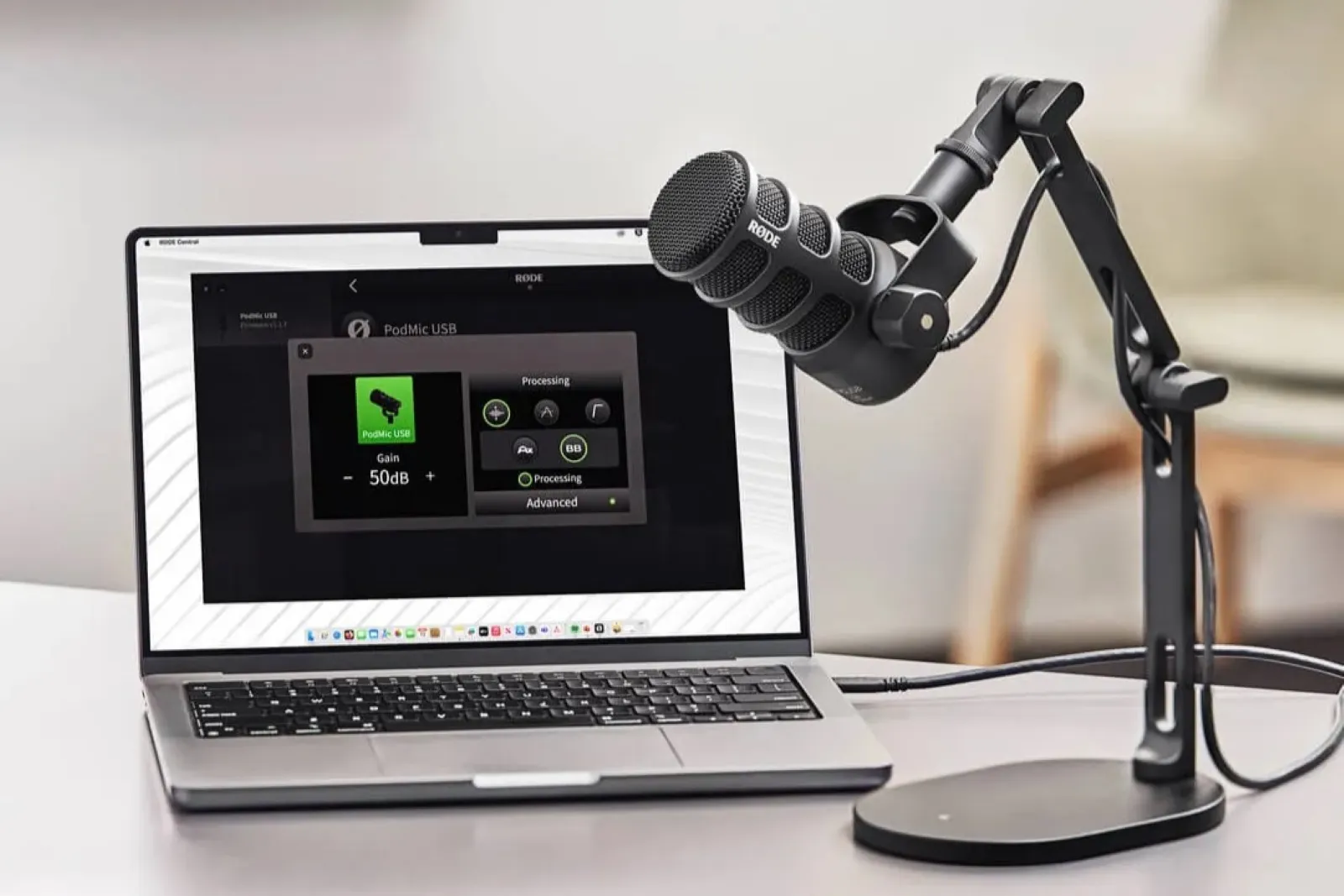 A professional podcasting setup featuring a high-quality USB microphone mounted on a boom arm next to an open laptop displaying audio editing software on a clean, modern desk.