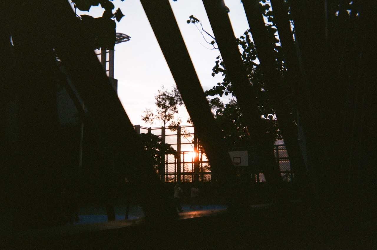 the sunset behind the bars of the basketball field