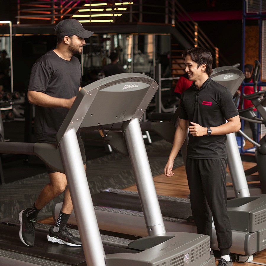 Man Running On ThreadMill With A Personal Training Coach