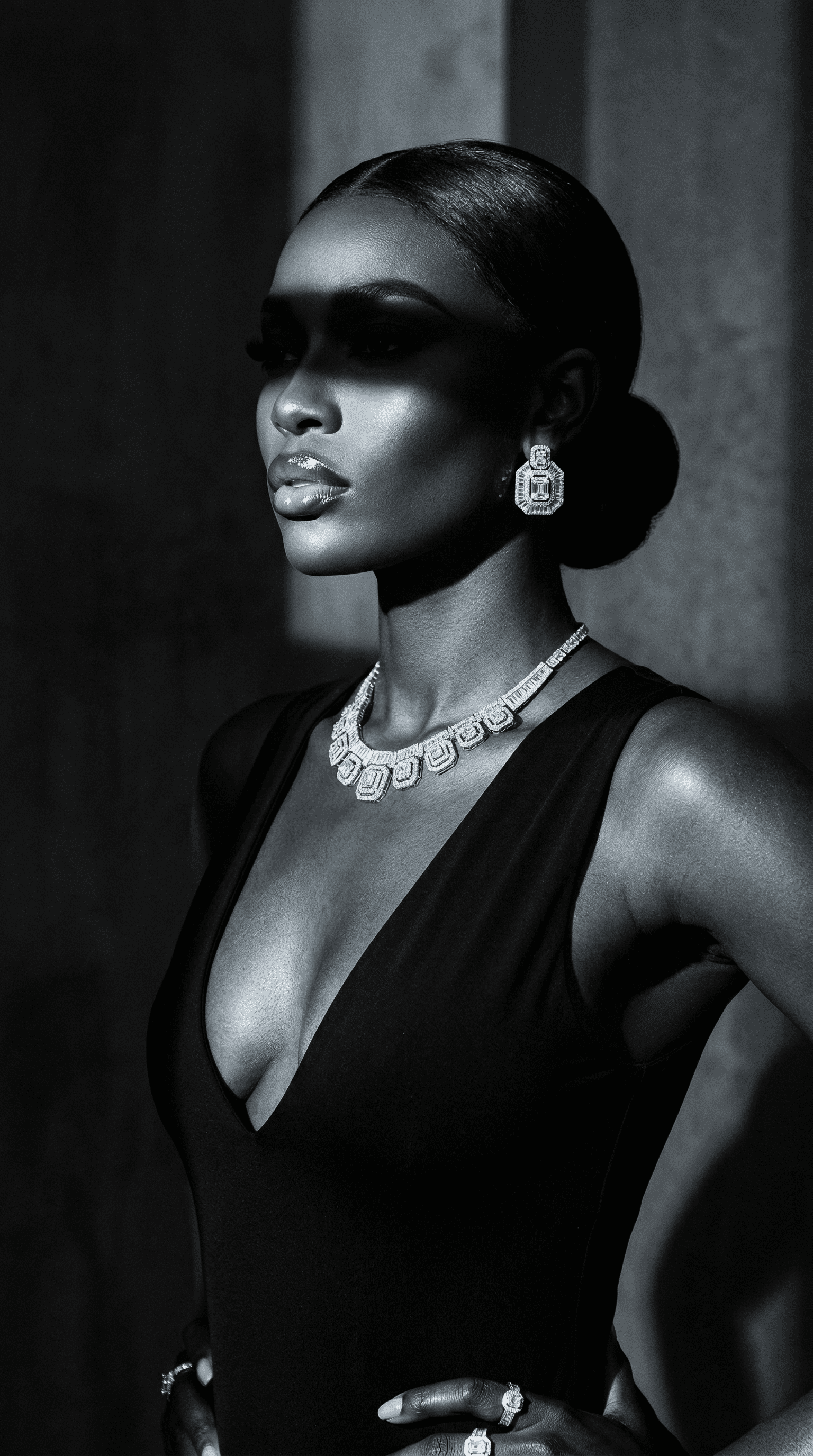 Monochrome portrait of woman wearing diamond earrings and necklace in high fashion lighting