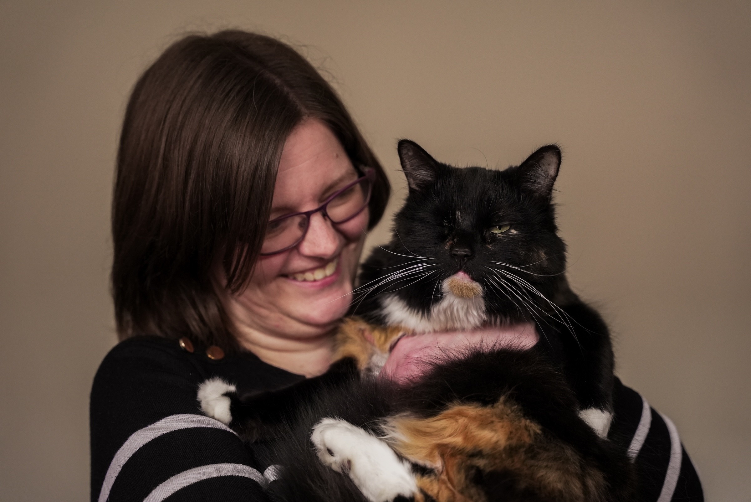 Woman smiling and affectionately holding her pet cat.
