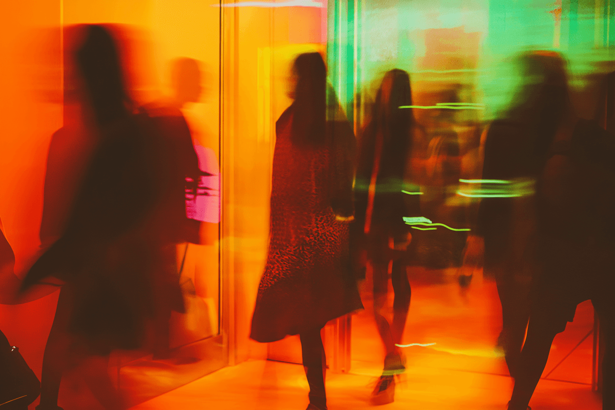 Silhouettes of figures against a warm orange and red concert light backdrop.