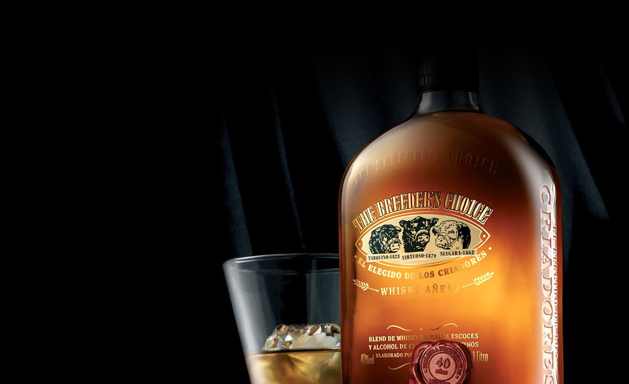 A dark, elegant bottle of Criadores whisky stands against a black background beside a glass filled with whisky and ice, conveying sophistication and luxury.