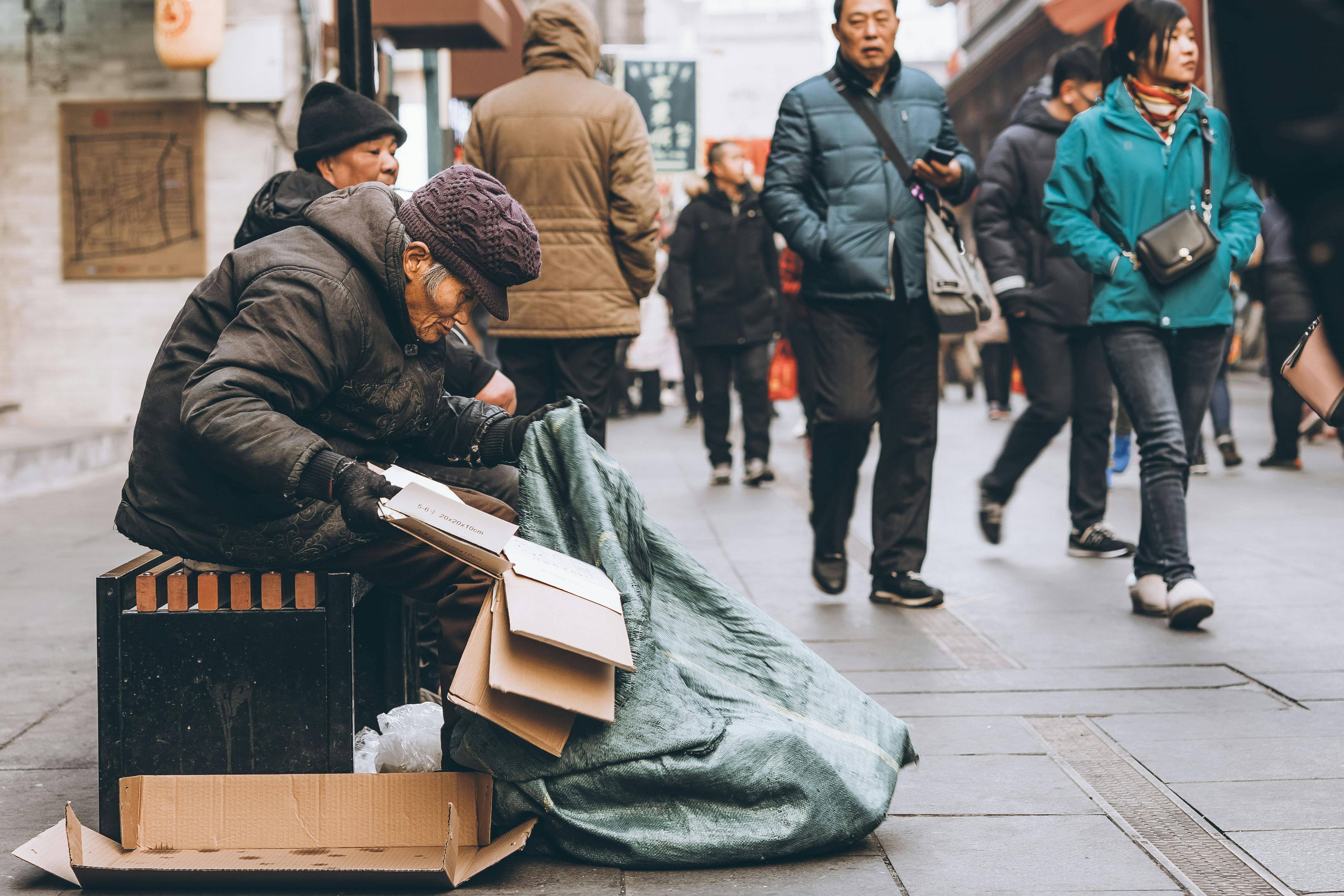 Elderly man collecting cardboard on a busy city street