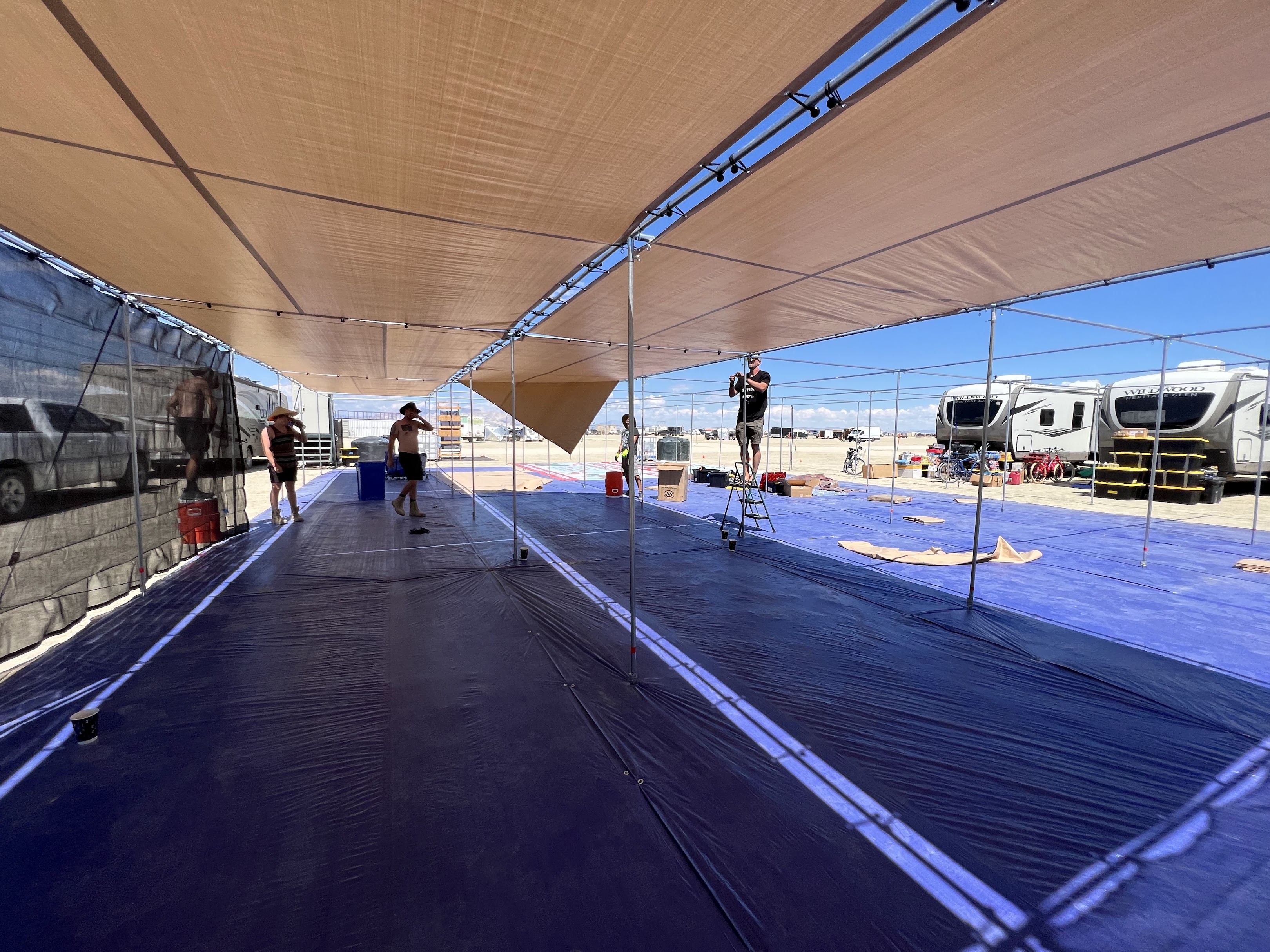 Large shade structure covering tents in a desert camp