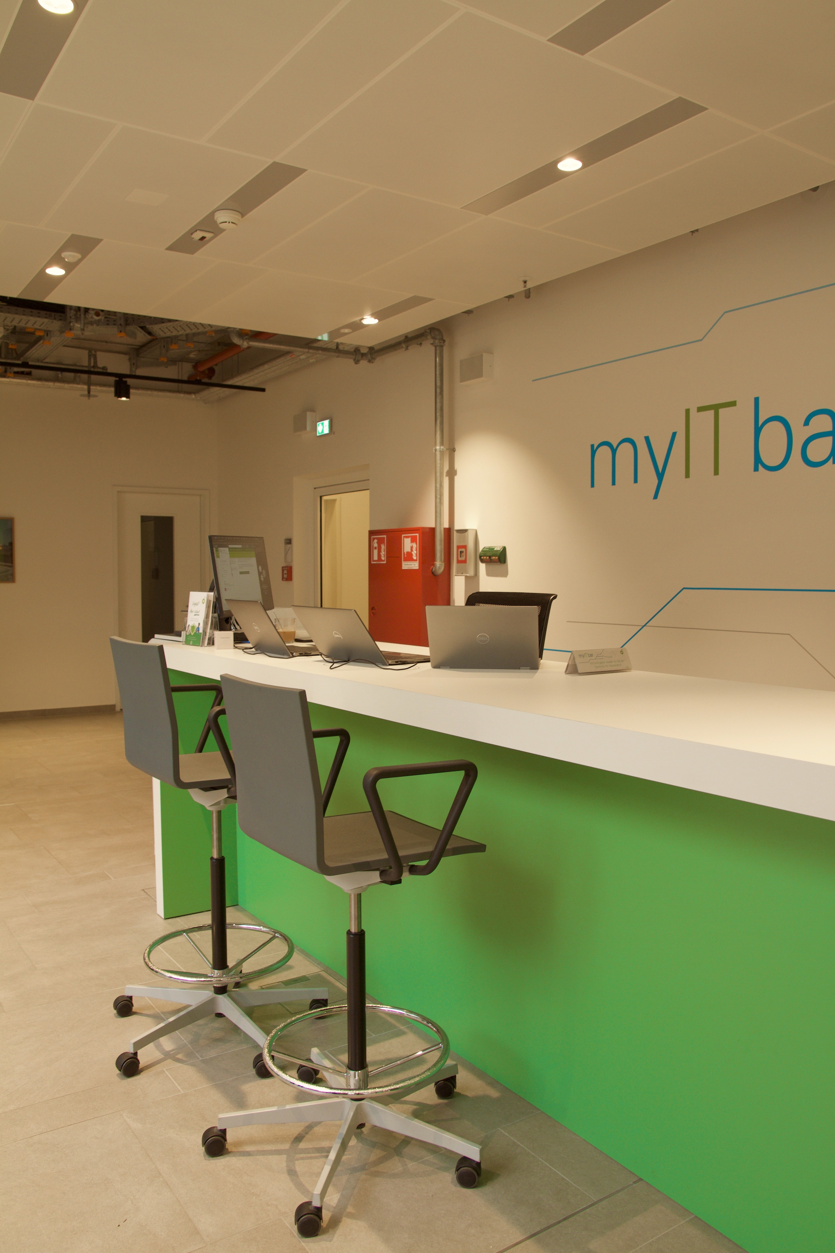 Moderner Empfangsbereich mit orangefarbener Akzentwand, schlankem Schreibtisch und offenem Grundriss.