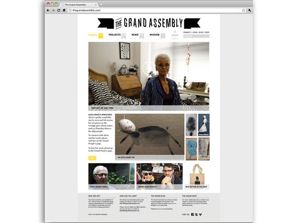 A screenshot displays a webpage titled “THE GRAND ASSEMBLY” on a Mac computer screen. The page features a central image of a woman with short gray hair, wearing a striped top. Below her image are several smaller images, including one of a white object resembling a head or mask, and several smaller portraits or photographs. To the right of these images are text blocks, including headings like “PEOPLE,” “PROJECTS,” “NEWS,” and “MISSION.” At the bottom of the page are navigation links, including “VISIT US!” and “VISIT VT.” The browser’s address bar shows “megrandassembly.com.”