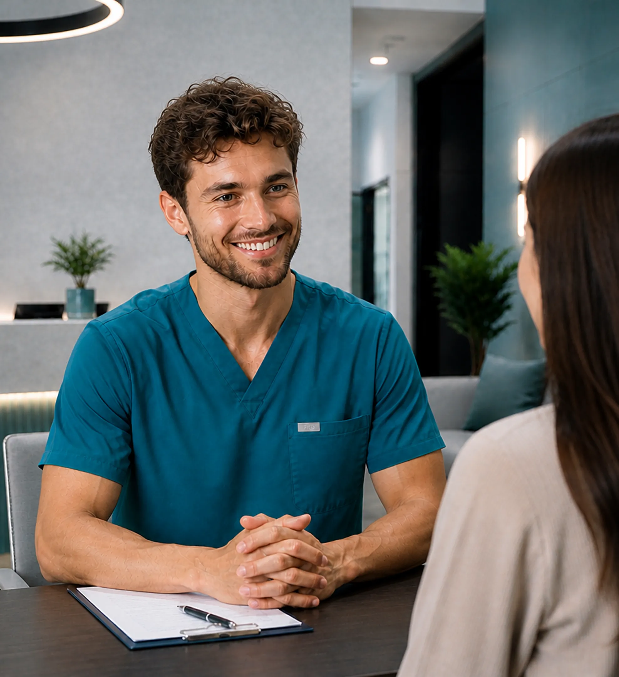 Dentist showing tooth model to smiling female patient during consultation.