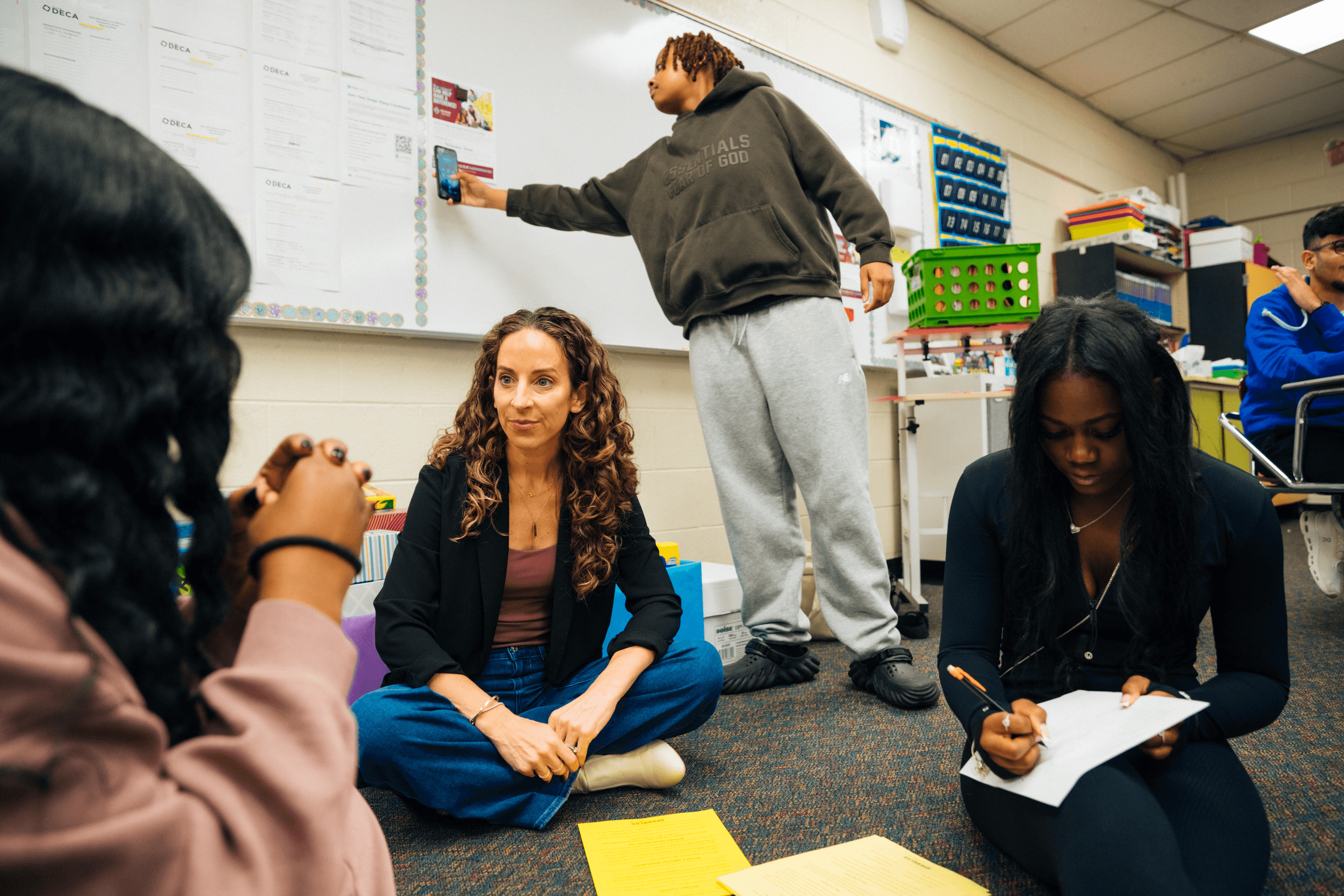 A woman with short curly hair wearing a black t-shirt looks into the camera.