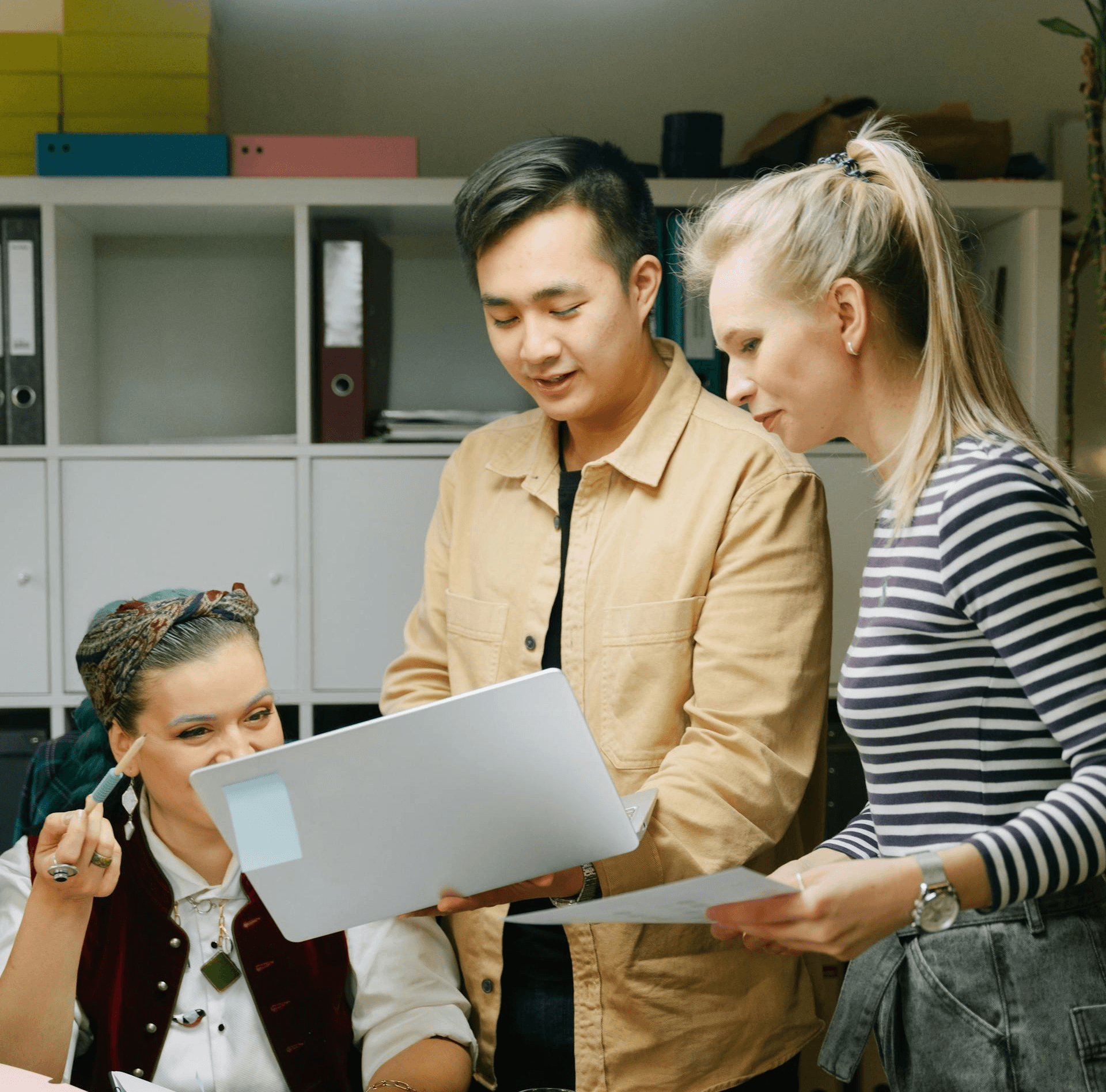 A team of 3 in office analyzing info on a laptop screen
