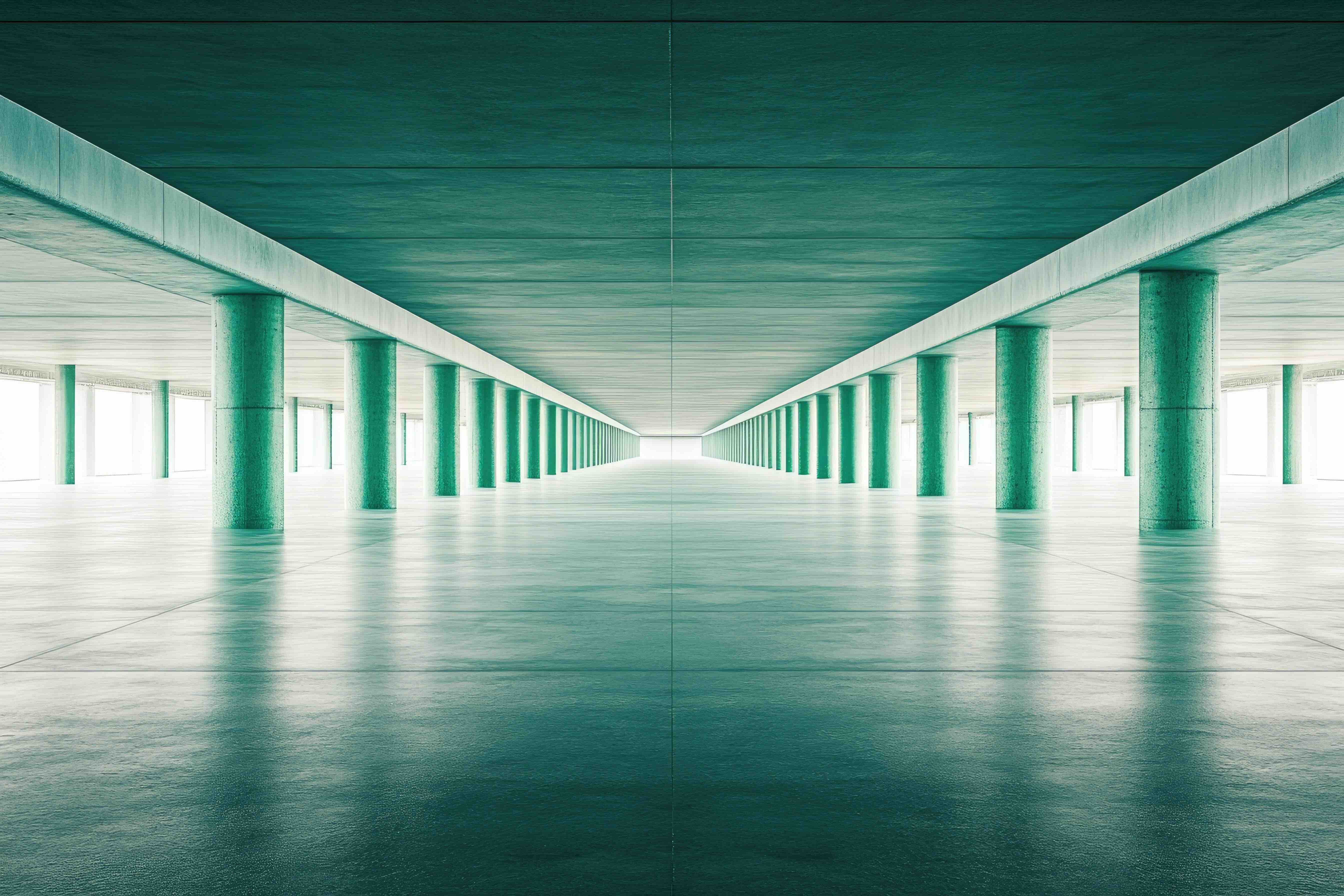 A long corridor with teal concrete columns leading toward light