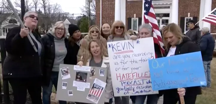 A group of protesters holding signs outside a building, expressing their views on an issue.