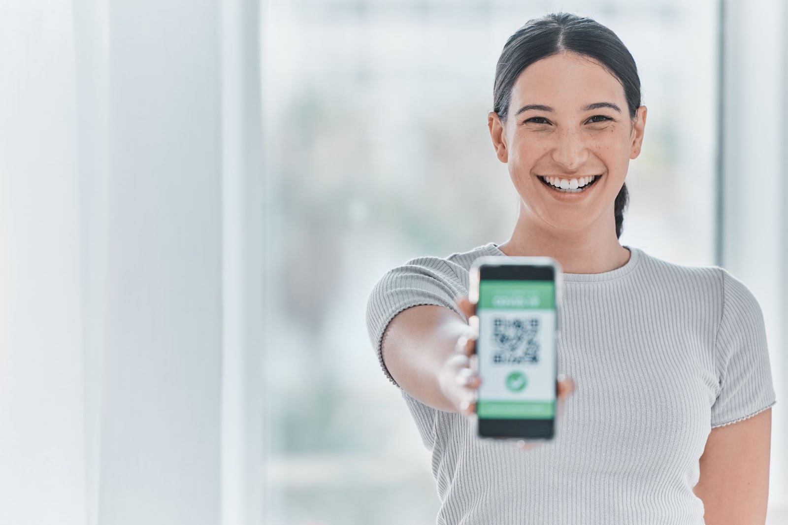 Woman holding out a phone with a QR code on the screen. 