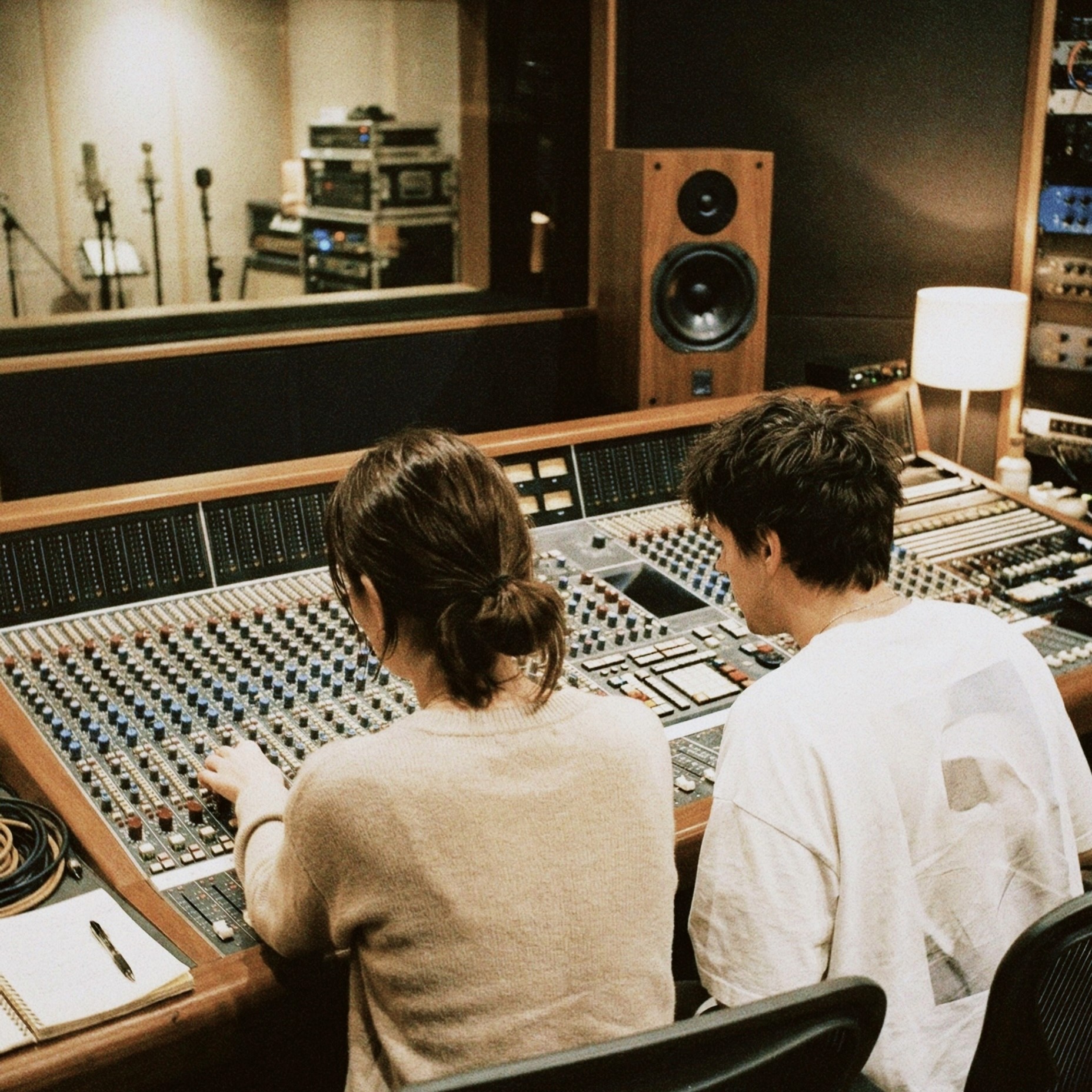 Dos personas produciendo música en mesa de mezclas en estudio