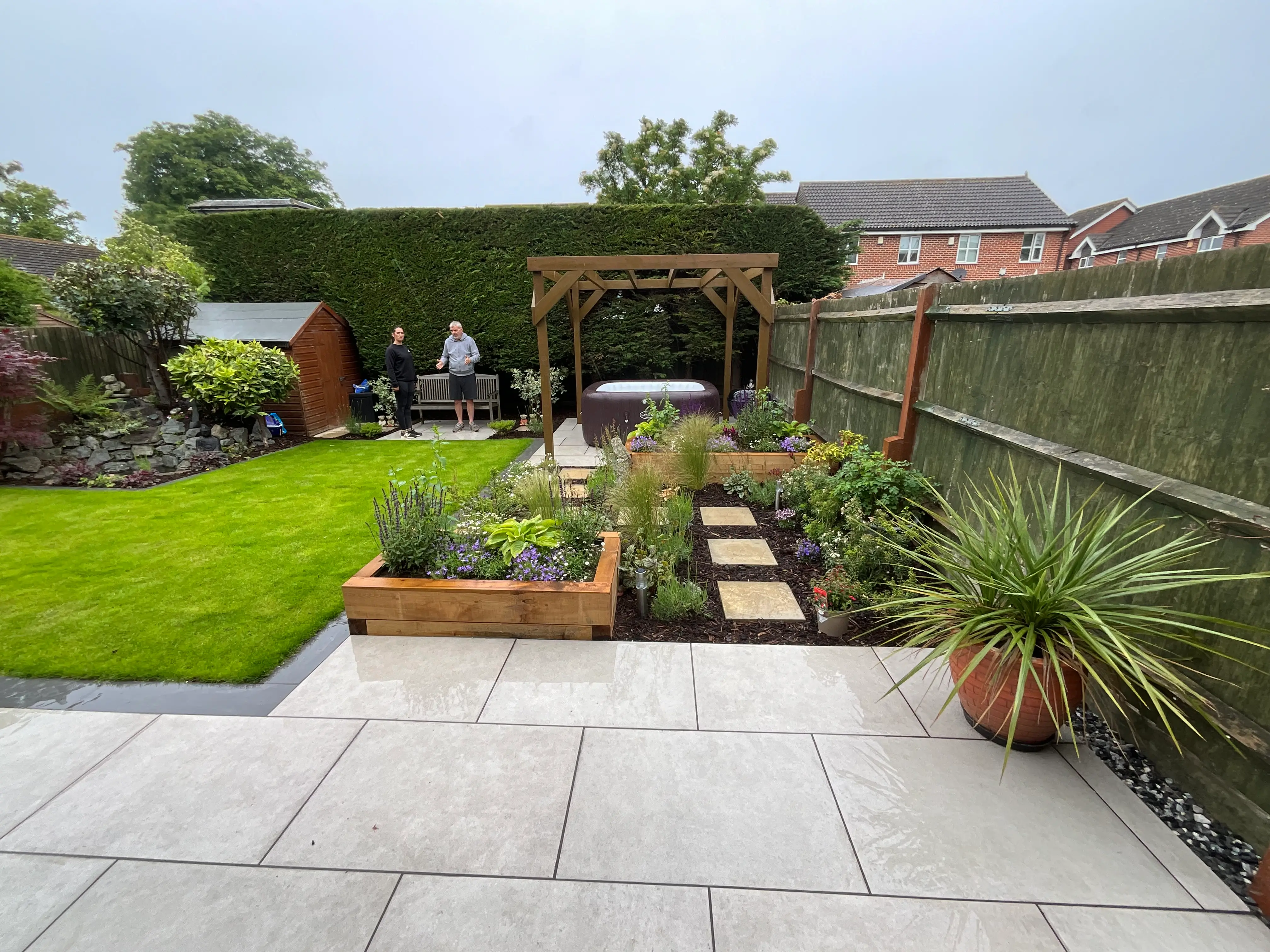 A well-maintained garden featuring green grass, flower beds, and a patio area with garden furniture.