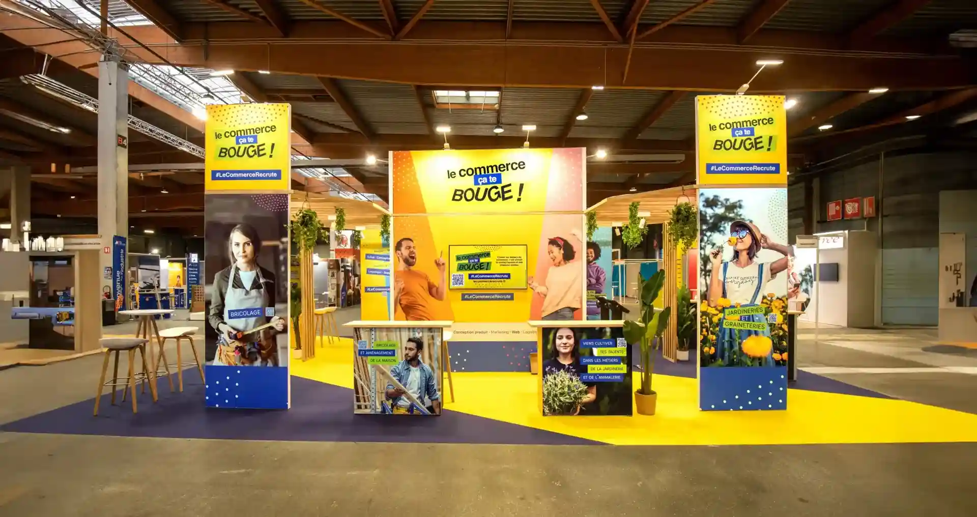 Vue d'ensemble du stand événementiel "Le Commerce, ça te bouge !", illustrant notre expertise en "Événementiel & Salons" via la conception 3D, la scénographie et la construction d'un espace immersif pour la promotion des métiers.