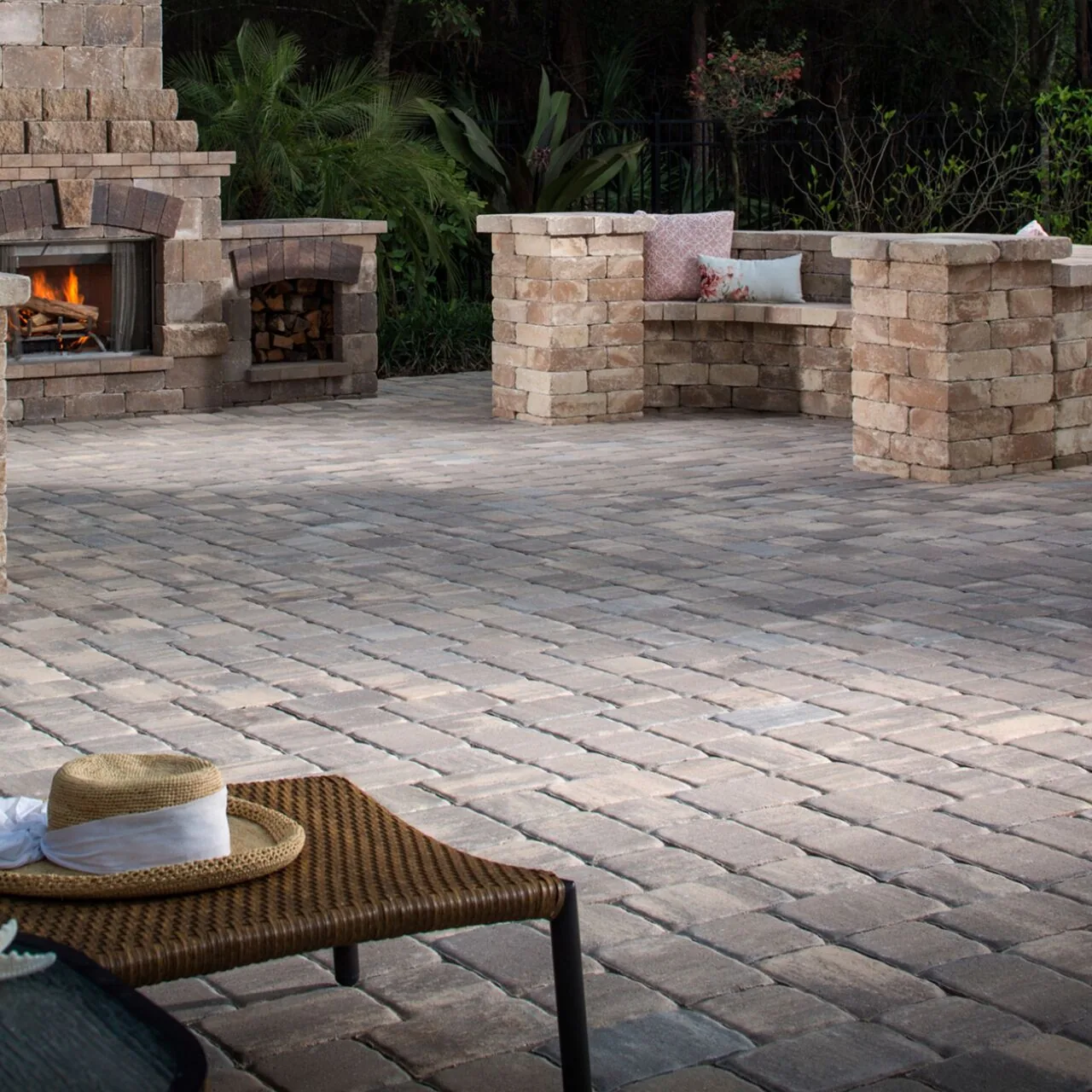 Paver terrace with an outdoor stone fireplace, garden walls and a lounge chair.
