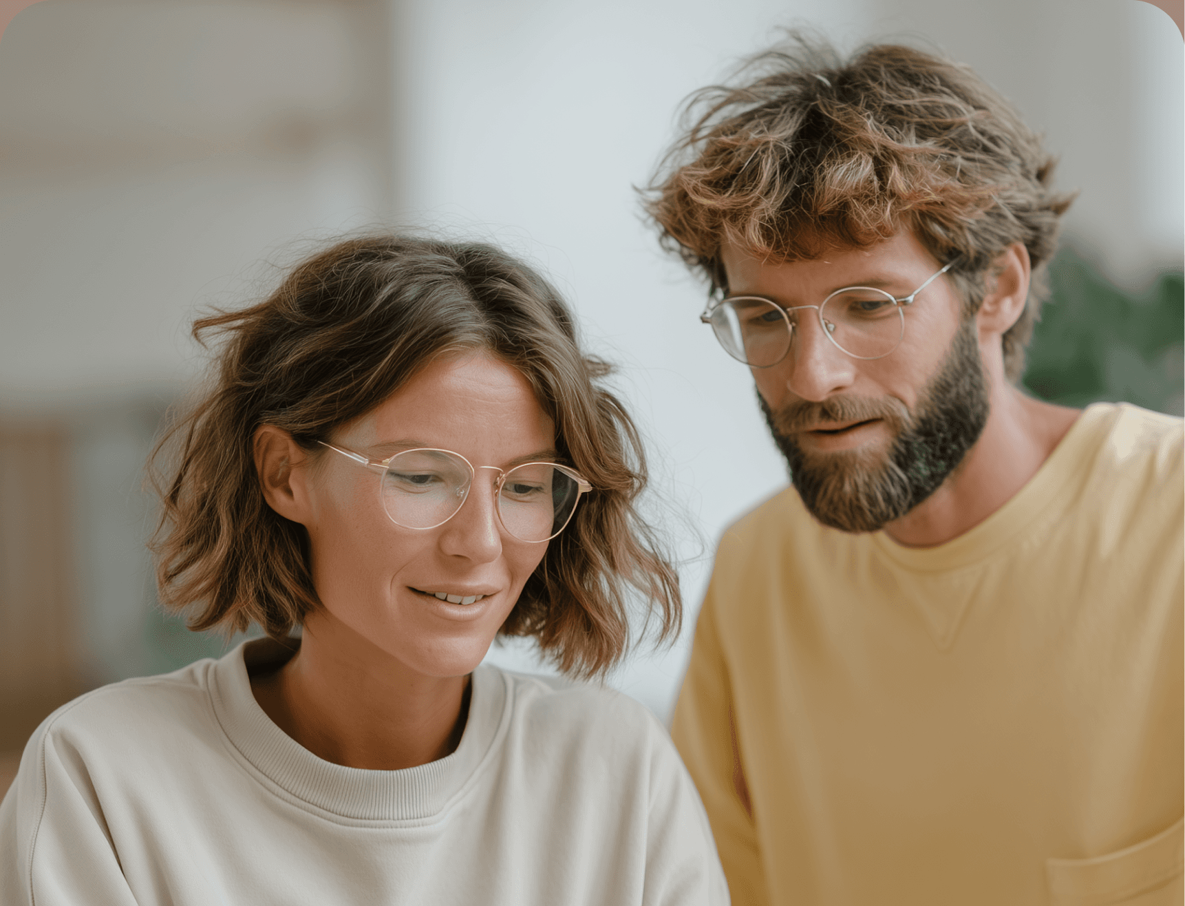 Man and woman with glasses looking at a screen.