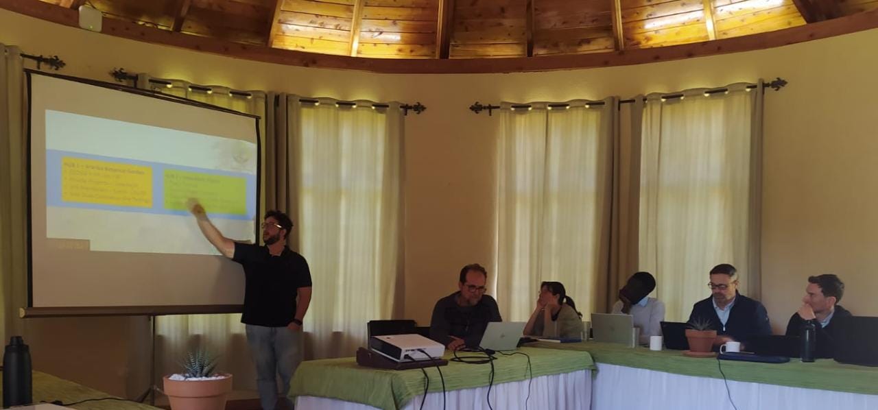 Homem apresenta dados em telão para participantes sentados a mesas durante reunião no Quênia