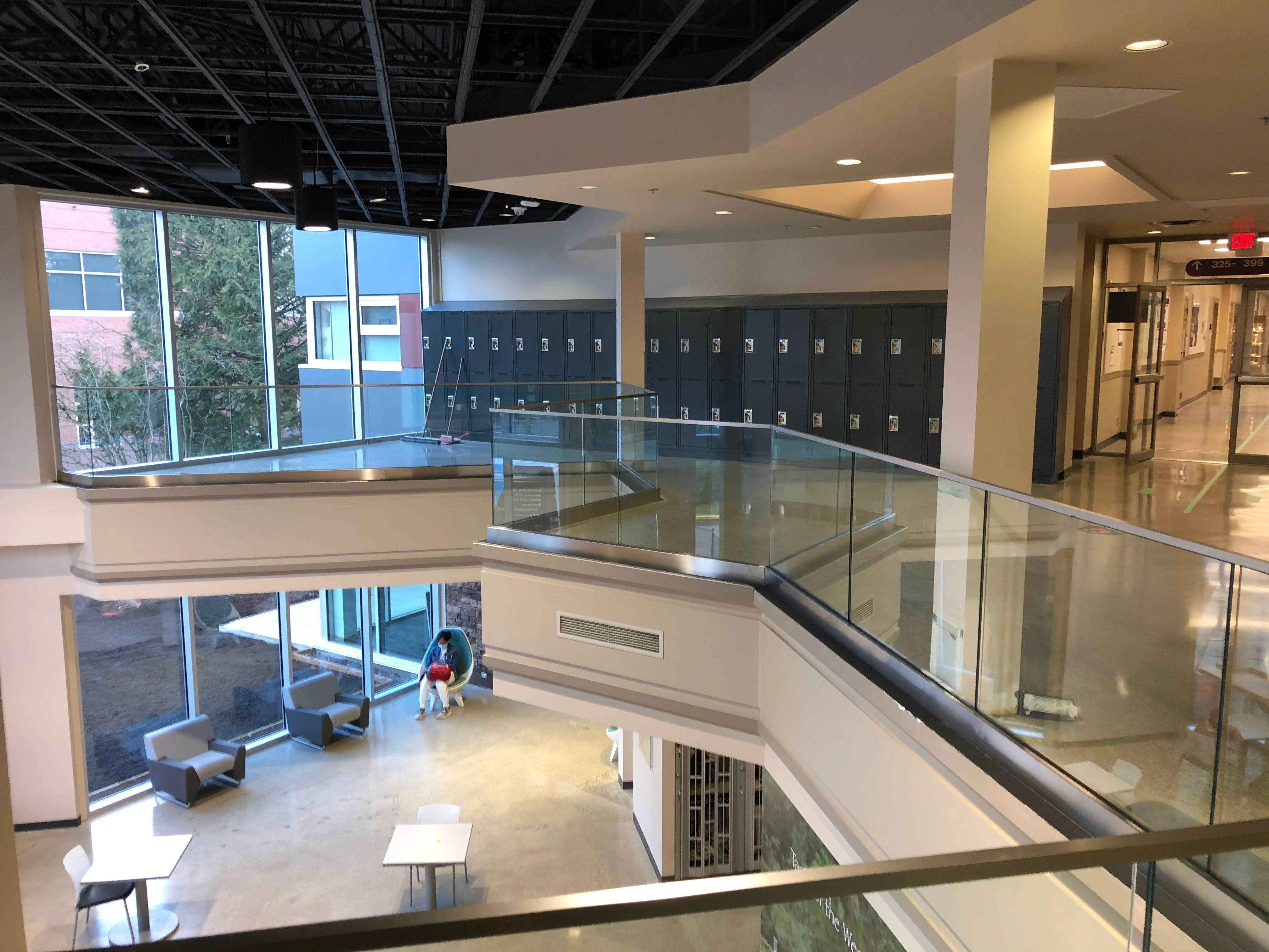 Frameless glass guardrail with a stainless top cap lining an upper-floor mezzanine walkway in a BC commercial building.