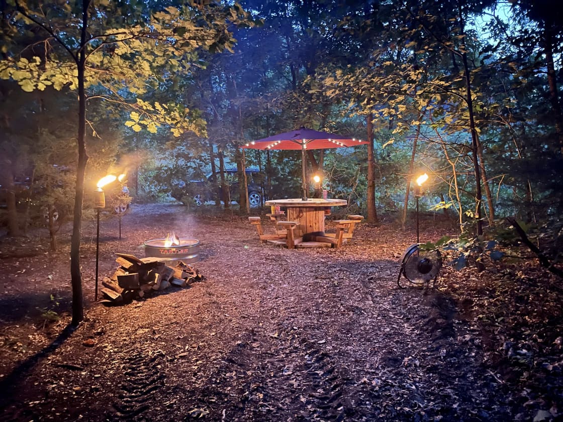 An outdoor table surrounded by forests lit up by torches