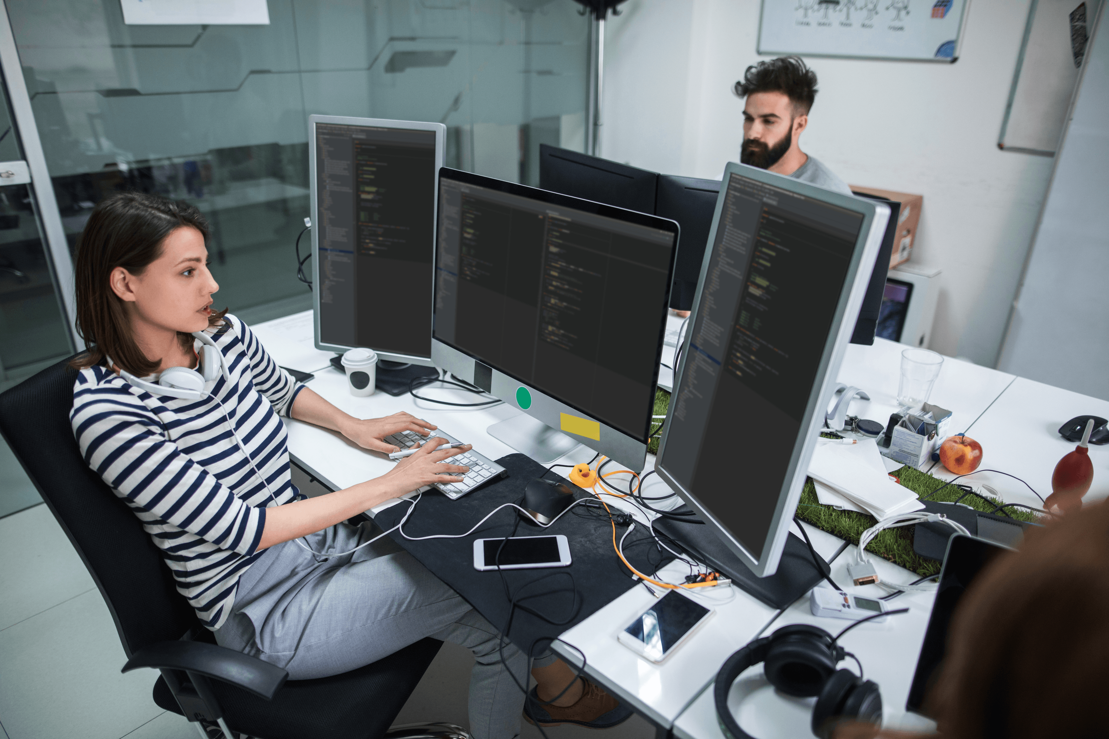 person coding on multiple screens - How Much Does It Cost to Hire an App Developer