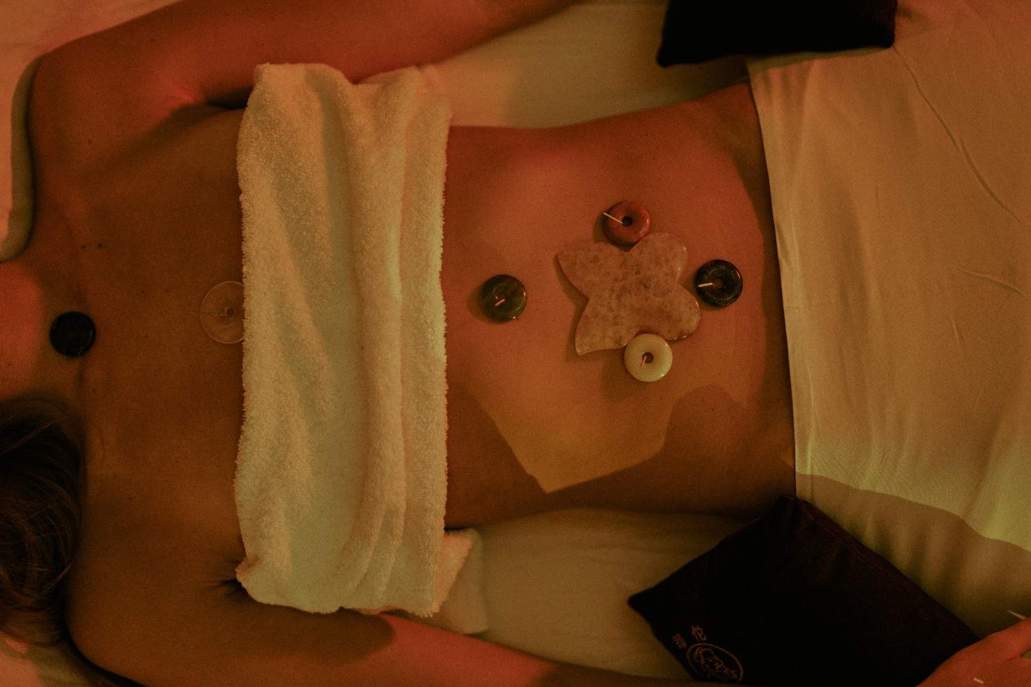 Massage stones and crystals arranged on a person's abdomen.