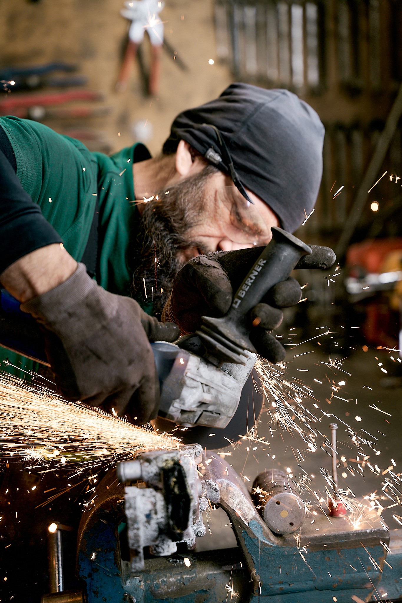 Ein Mann schleift Metall mit einem Winkelschleifer, Funken fliegen. Nahaufnahme des Handwerkers bei der Arbeit.
