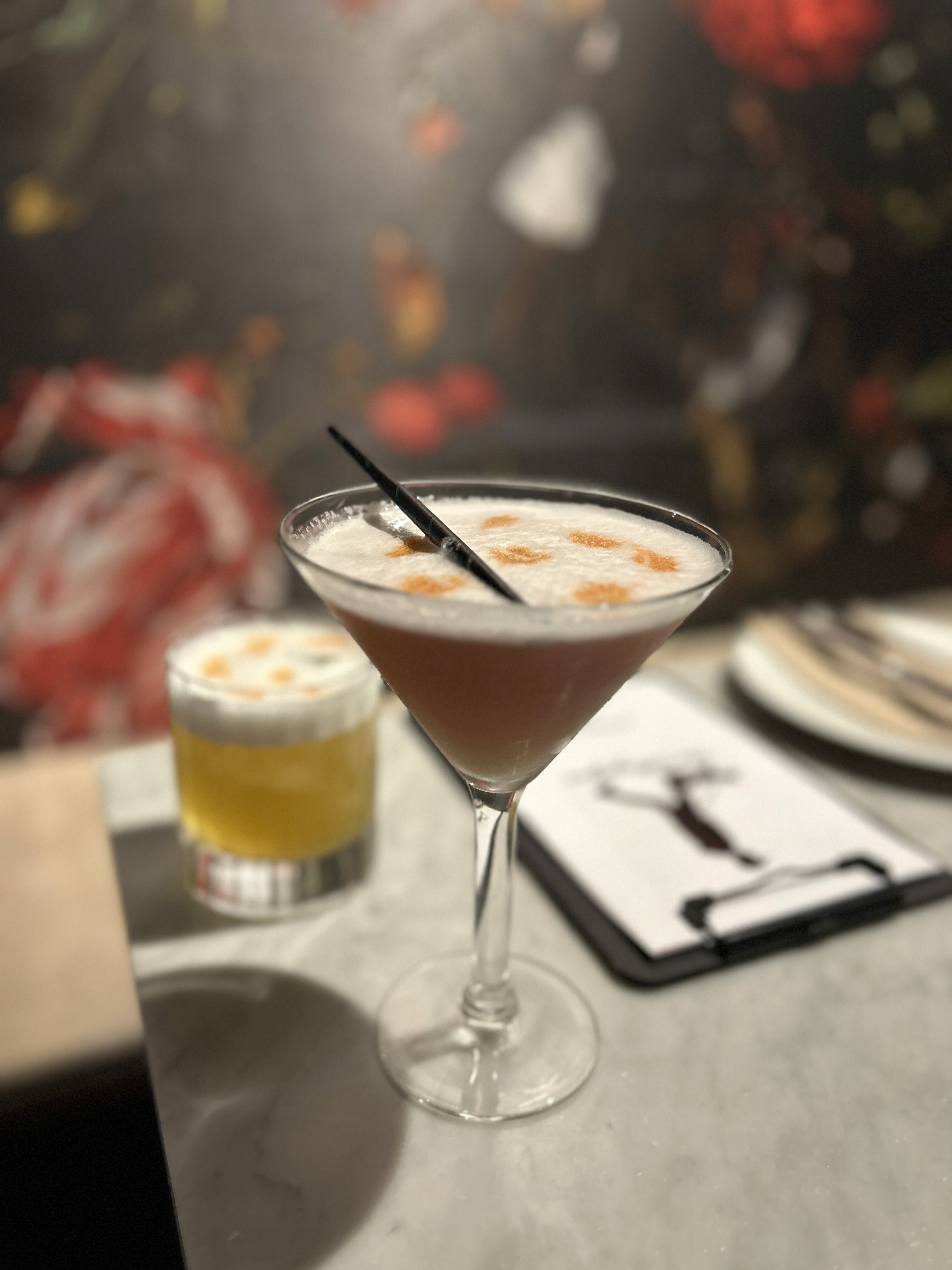 a glass of cocktail with a slime orange fruit