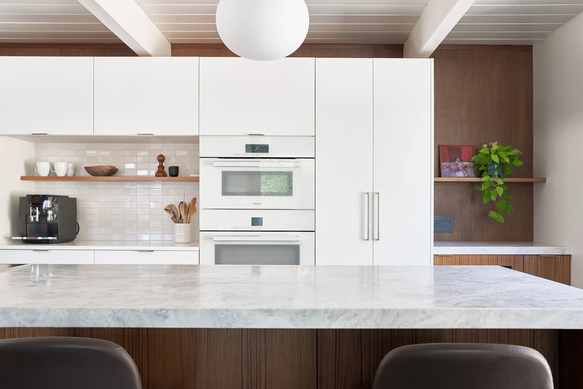 Closeup of the oven wall over the kitchen island, showcasing the Miele appliances and elegant design in the Eichler kitchen remodel. Photo by Todd Huge.