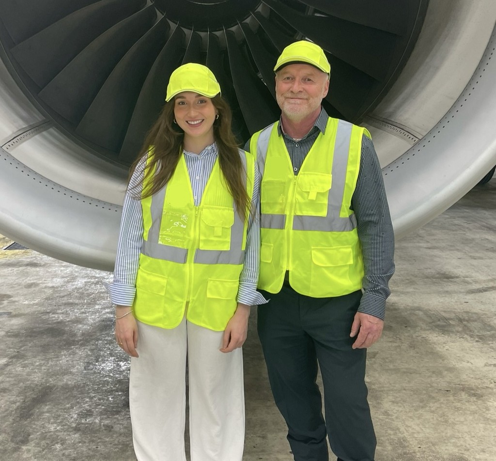 Photo of the founders of Exoskeletons Canada during a client visit, posing in front of an aircraft engine.

