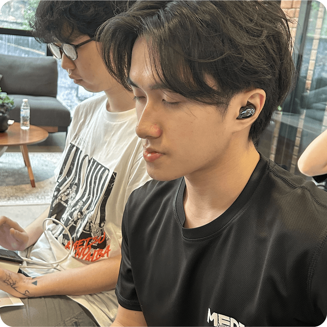 A young man in a black t-shirt with his eyes closed