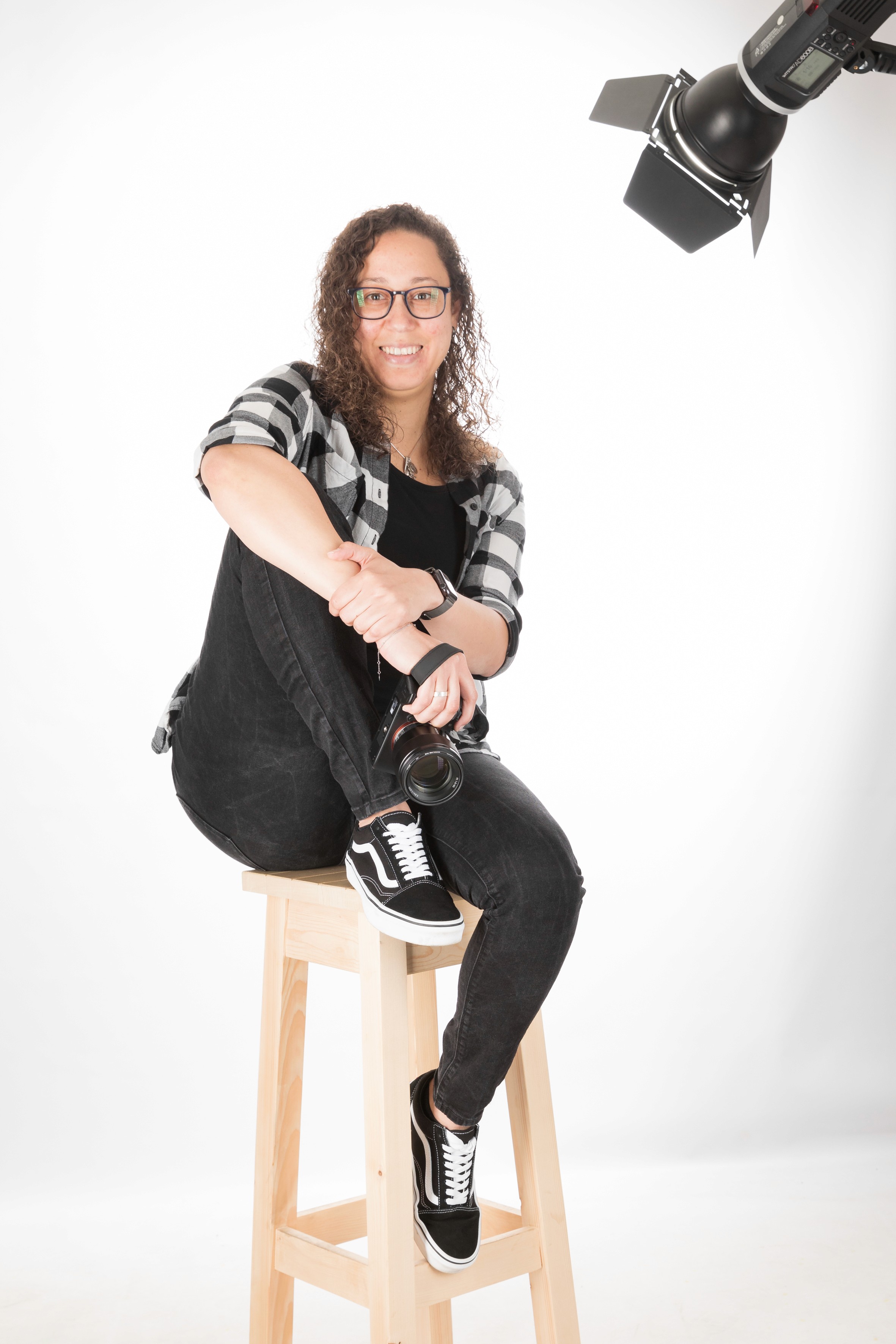 A person with short blonde hair holds a vintage camera.